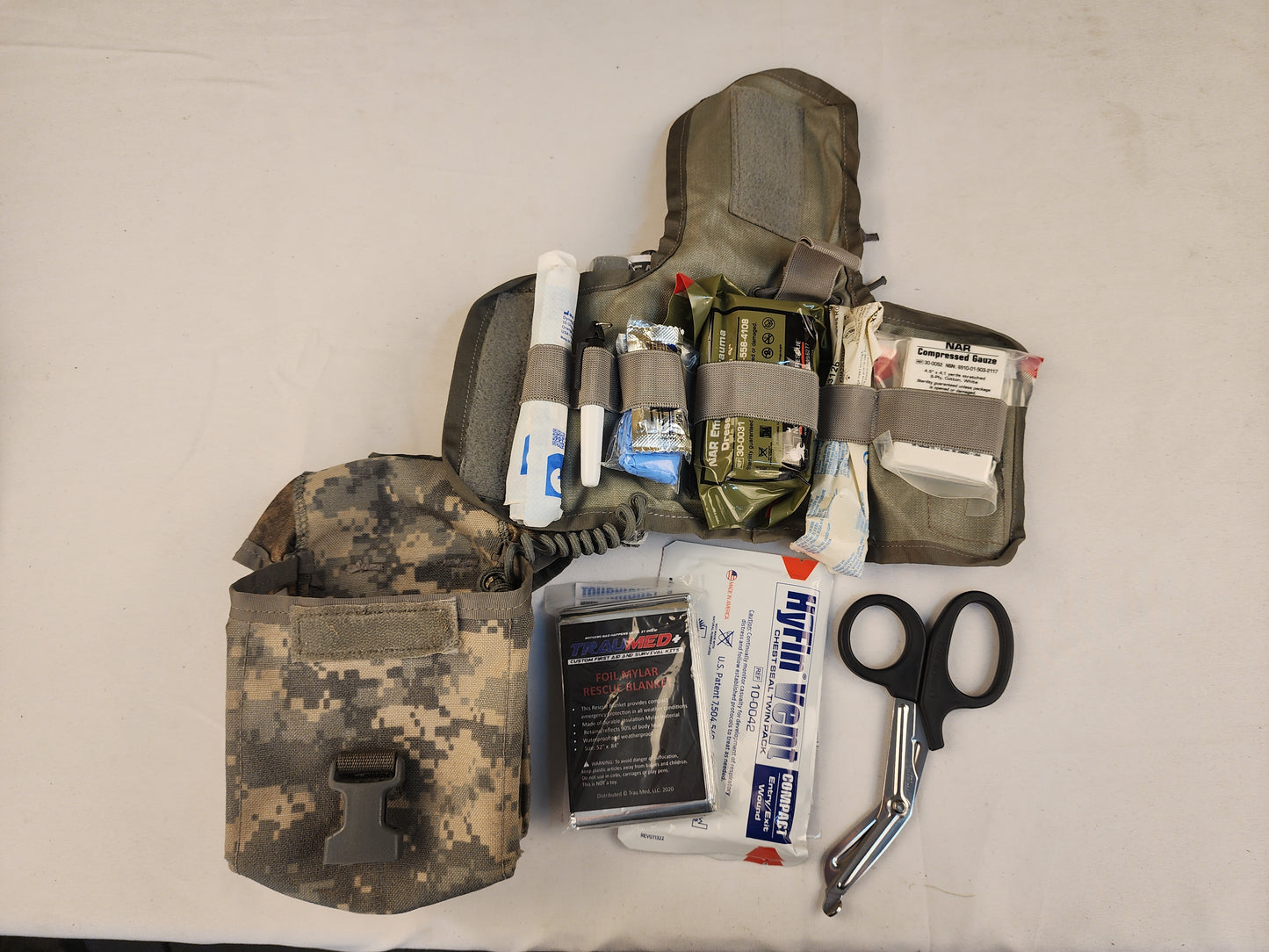 Camouflage tactical pouch with medical supplies on a white background