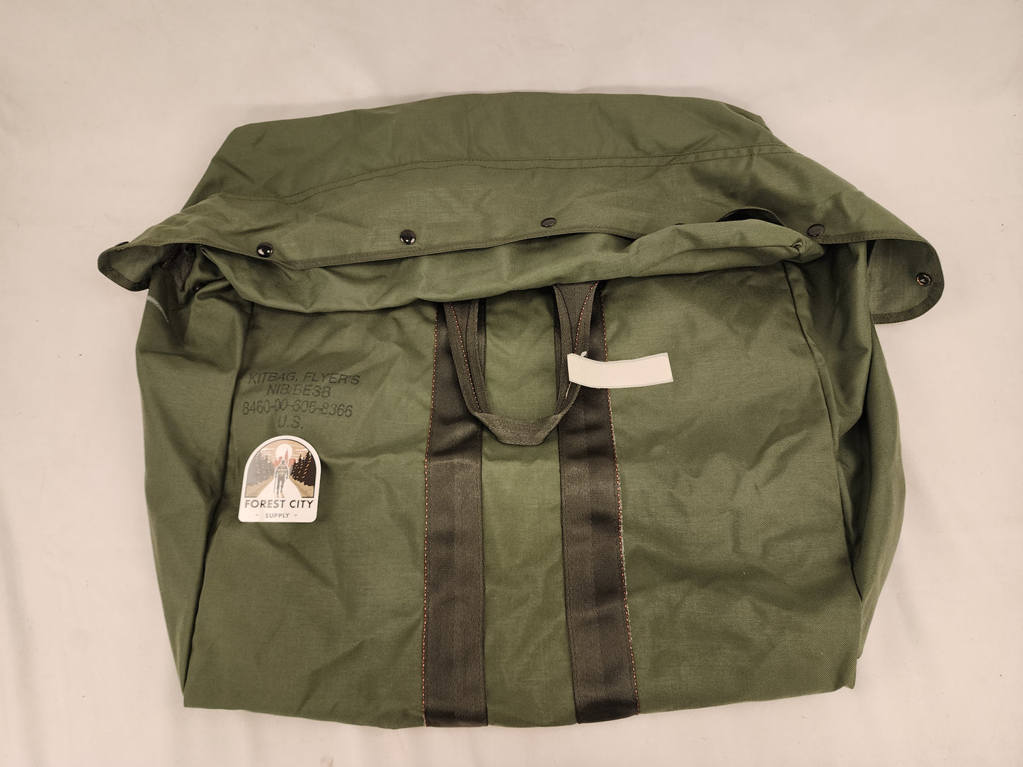Olive drab green military-style duffel bag with a label indicating 'U.S. Government Issue'.