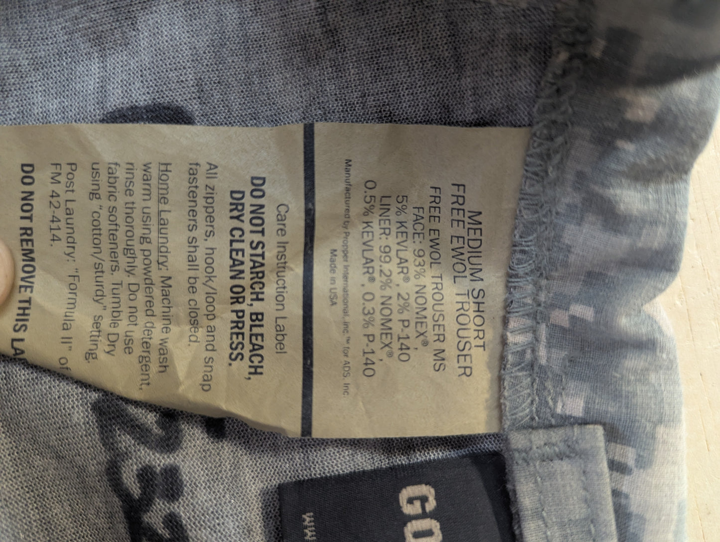Close-up of a denim garment label on blue jeans, showing care instructions and size information including 'MEDIUM SHORT'.