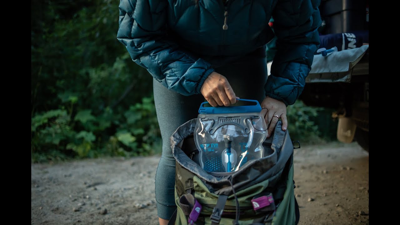 A photo of a hydration bladder being taken out of a hiking bag by a person