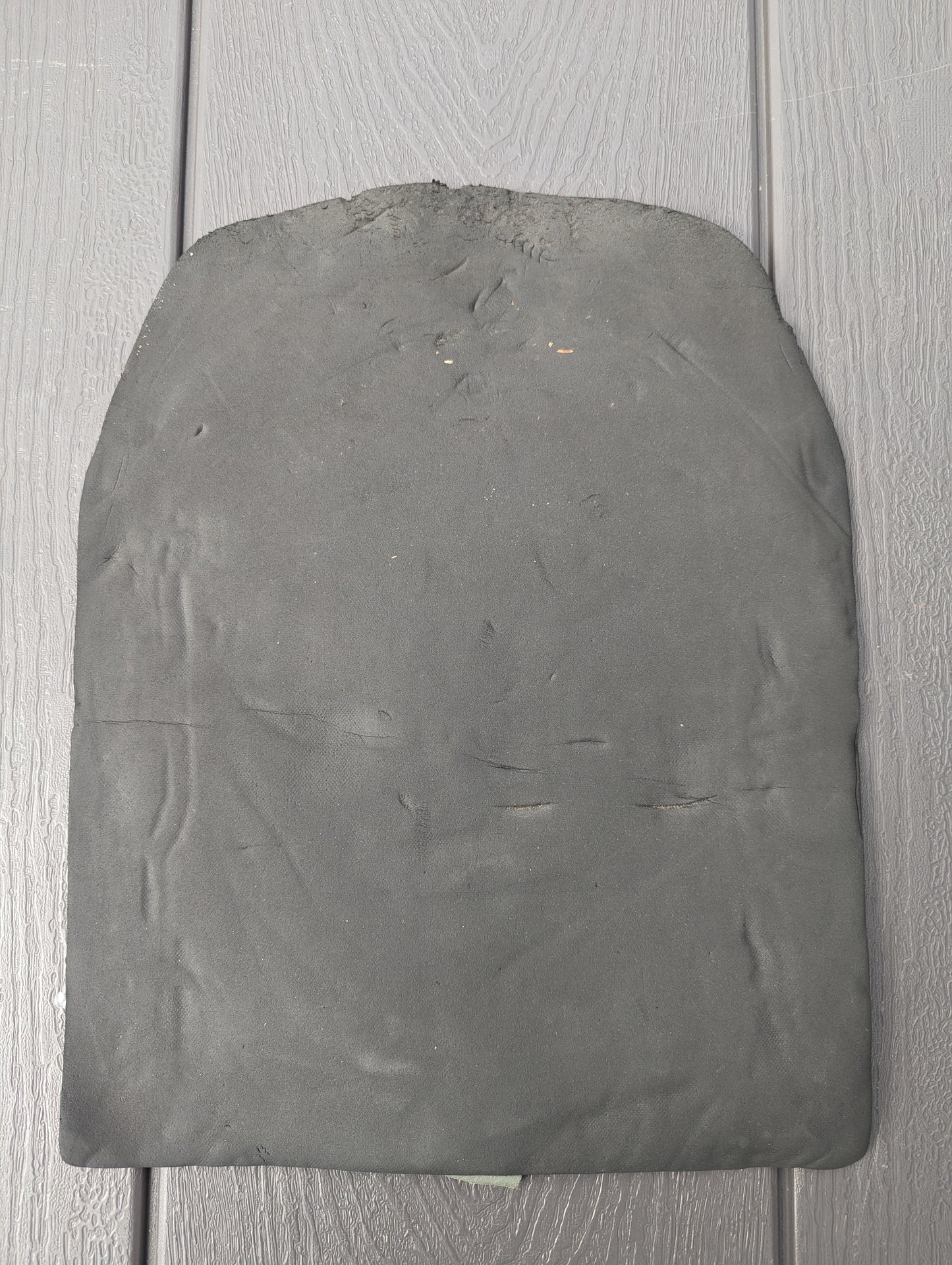 A single, black, molded foam comfort pad insert for the U.S. Military Surplus Assault Pack, resting on a dark, ridged background.