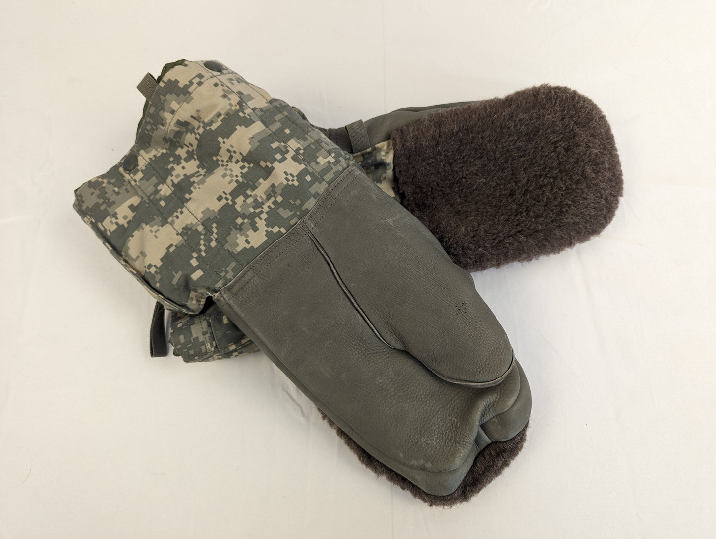 A pair of U.S. Military Extreme Cold Weather Mittens laid flat, featuring dark olive suede palms, ACU digital camouflage gauntlets, and thick, dark brown fur lining visible at the cuff.