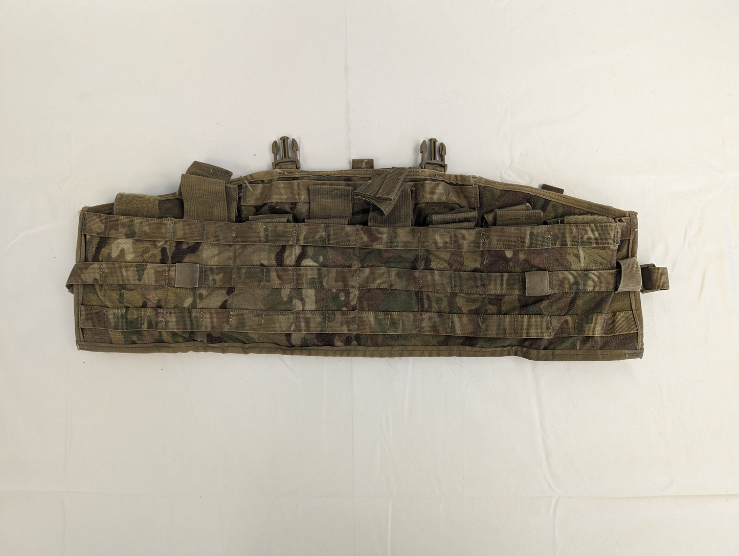 A U.S. Military Surplus Tactical Assault Panel or Chest Rig in OCP/Multicam camouflage, laid flat, featuring multiple segmented pockets secured by webbing straps and extensive horizontal MOLLE webbing.