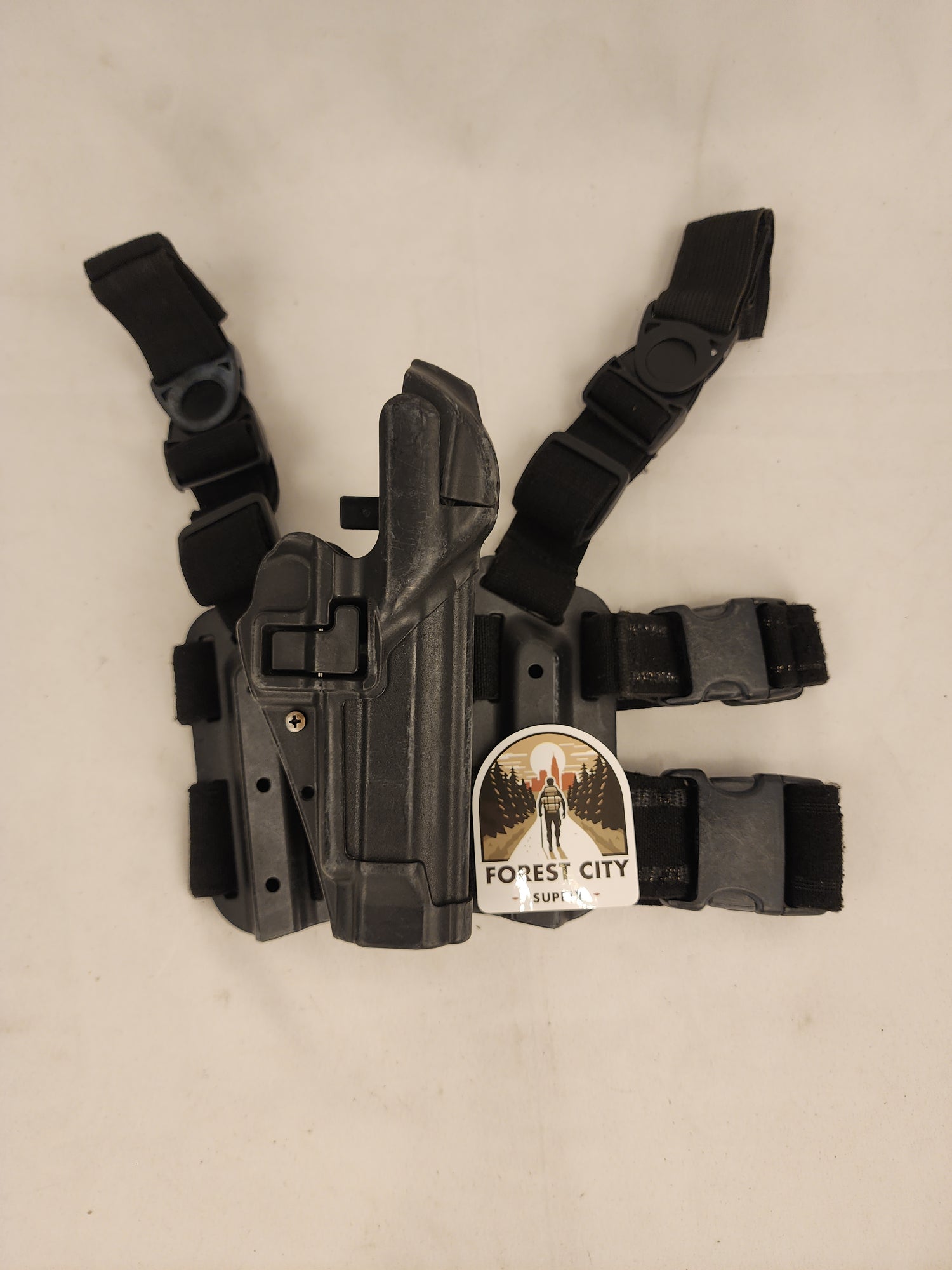 Black BlackHawk pistol holster with adjustable straps and a label indicating 'U.S. MILITARY SURPLUS'.