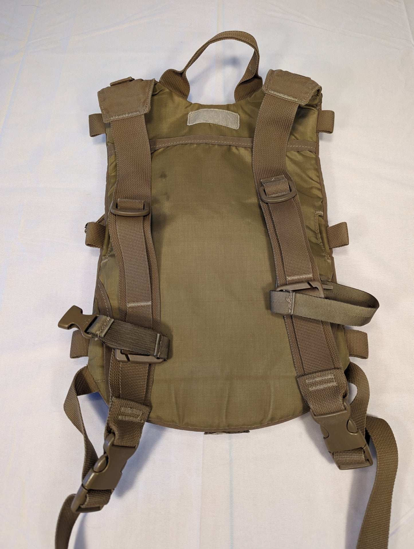 Brown tactical vest with multiple straps on a white background