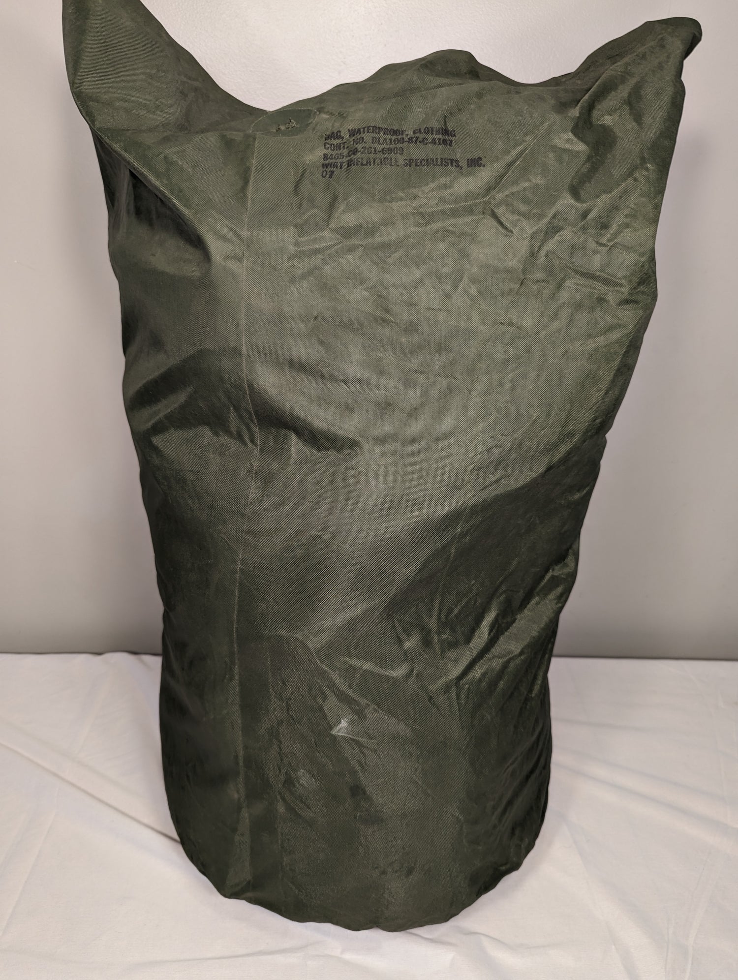 A green waterproof clothing bag with a military label visible on it.