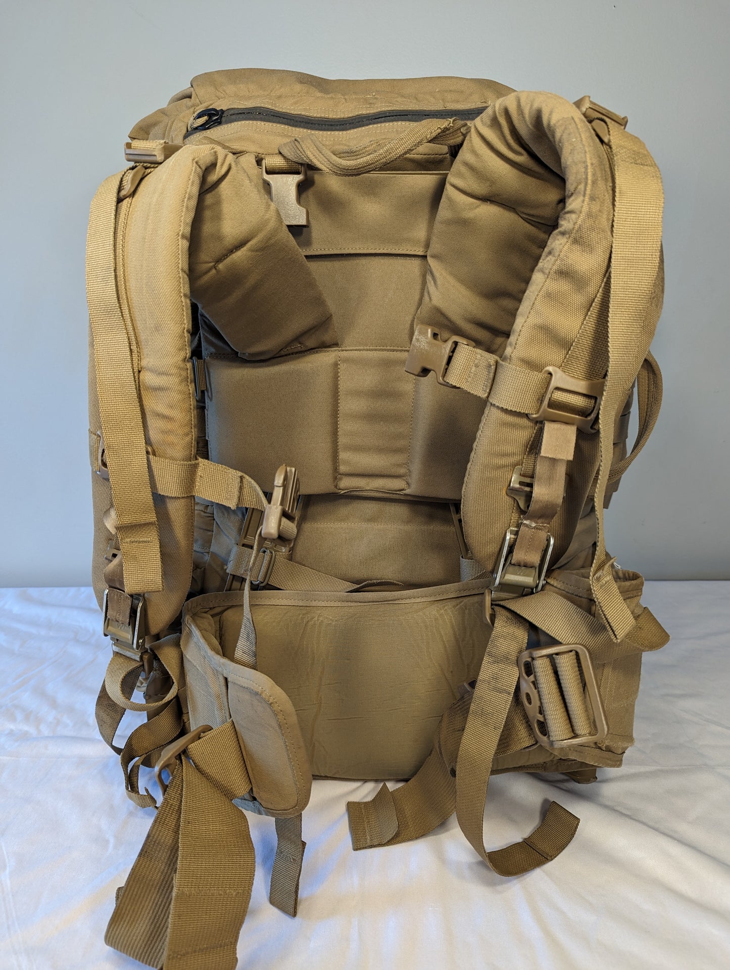 Tan military-style backpack on a white background