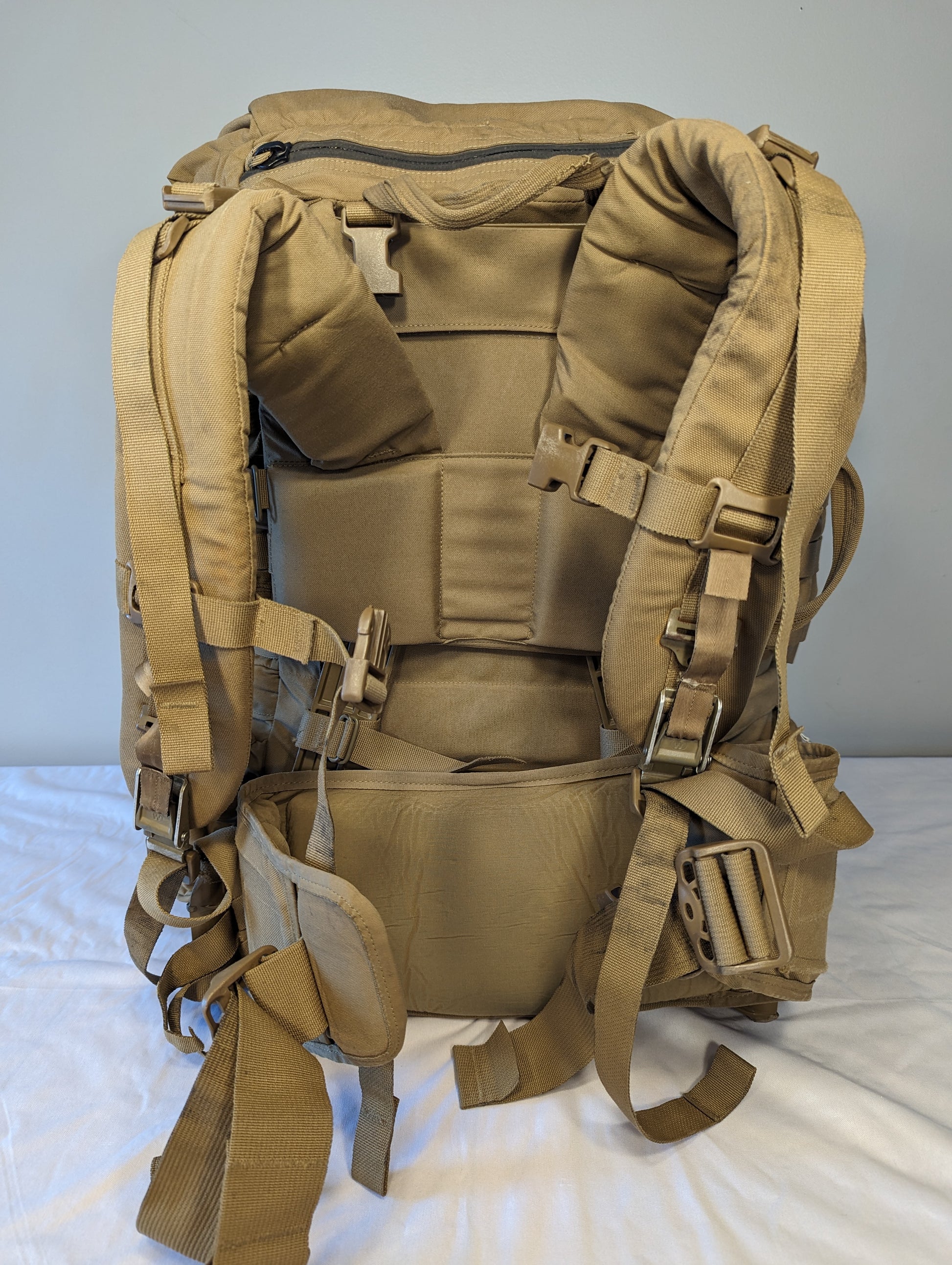 Tan military-style backpack on a white background