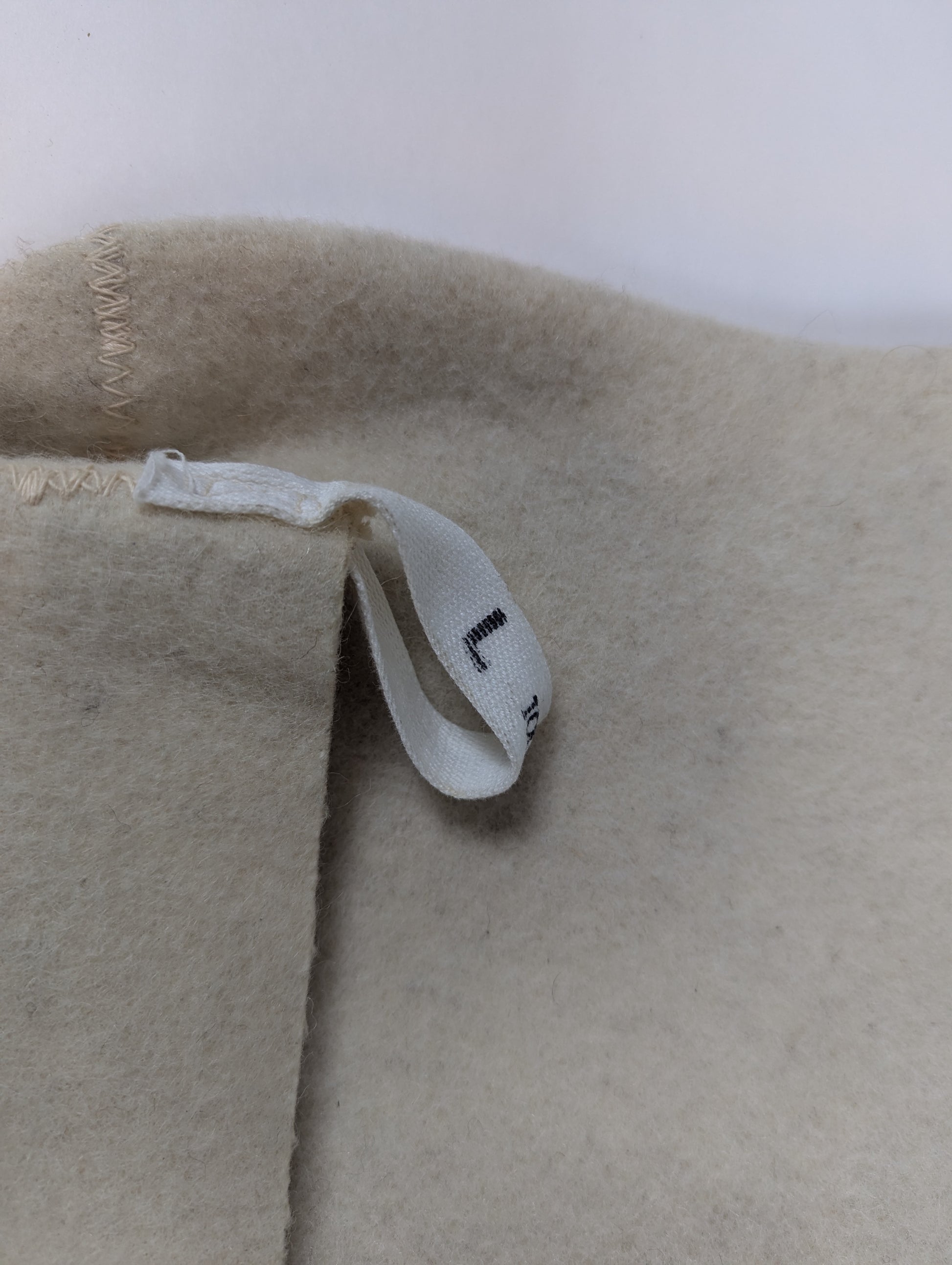 Close-up of beige fabric with a label on a white background