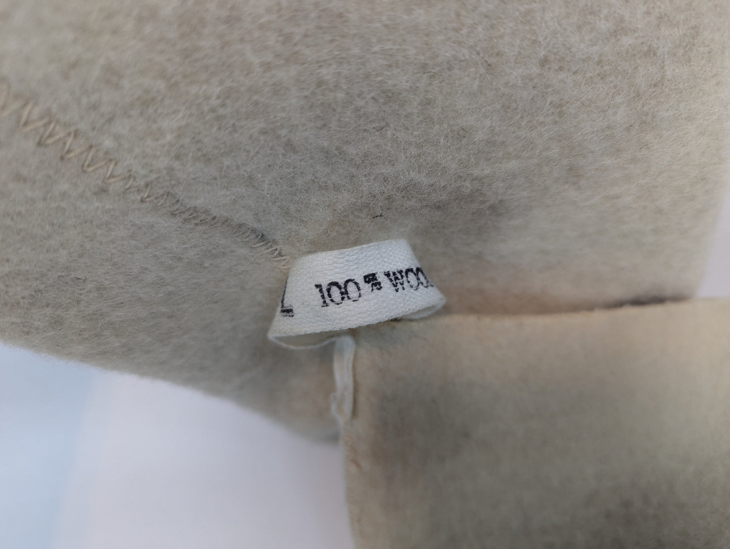 Close-up of a beige fabric with a label indicating '100% Wool'.