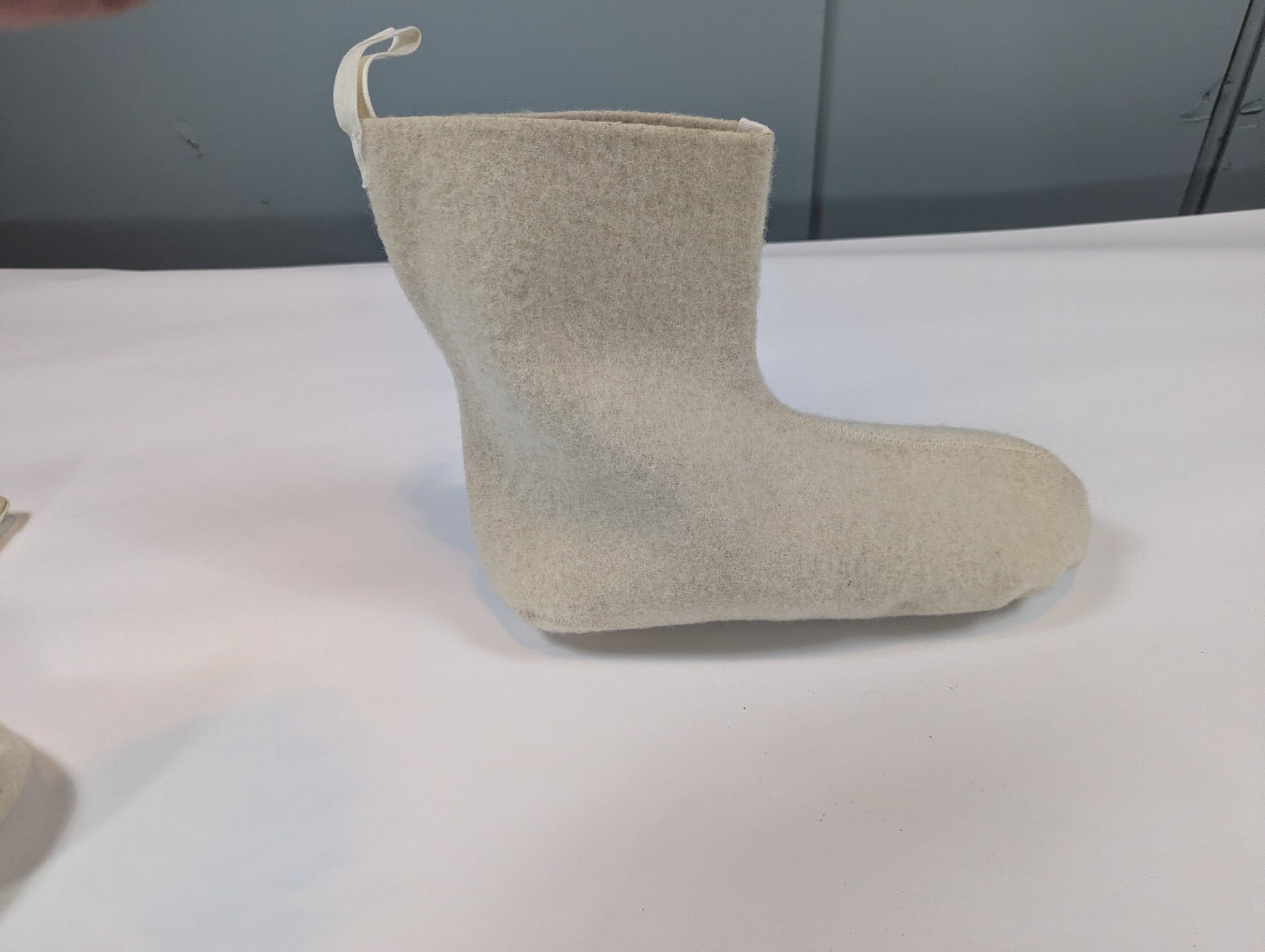 Beige boot on a white surface with a gray background