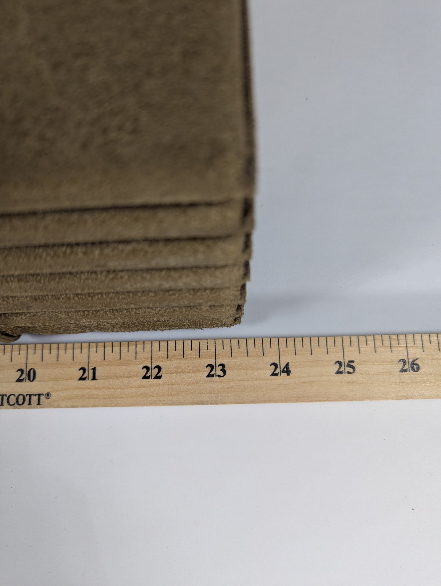 Stack of brown cardboard sheets with a ruler for scale on a white background
