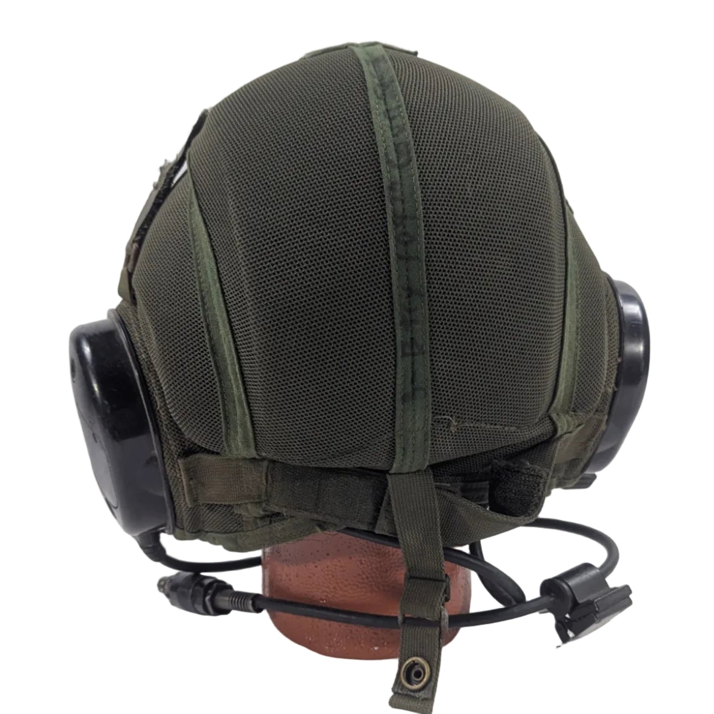 Green military helmet with black visor on a white platform against a white background