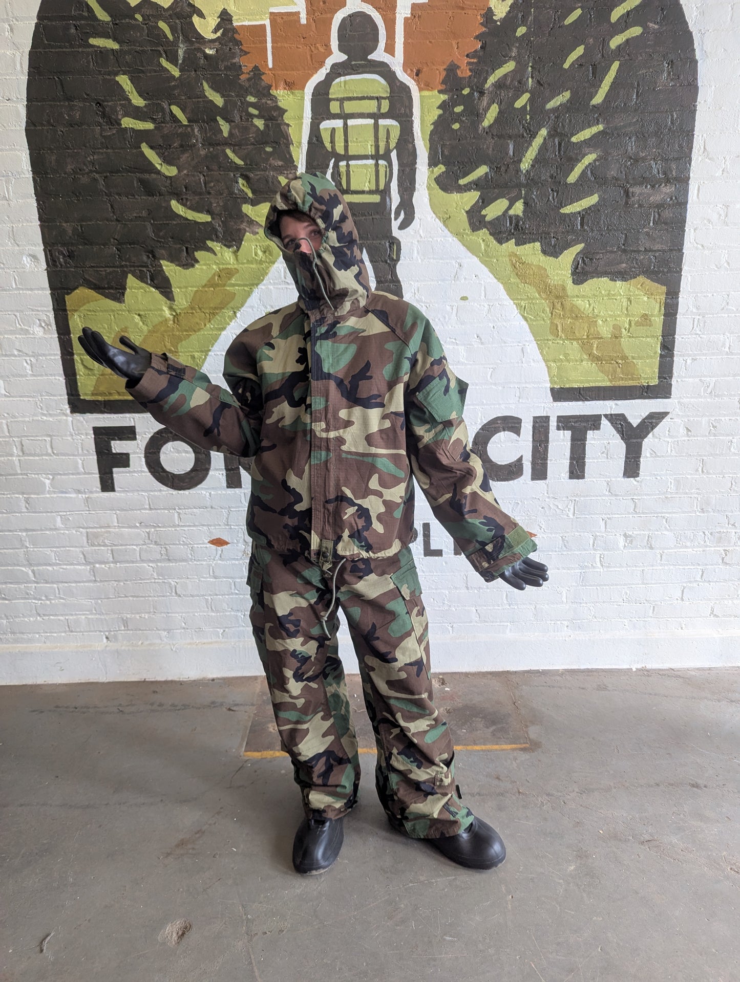 Person wearing a camouflage suit standing in front of a mural with 'Fortitude City' text.
