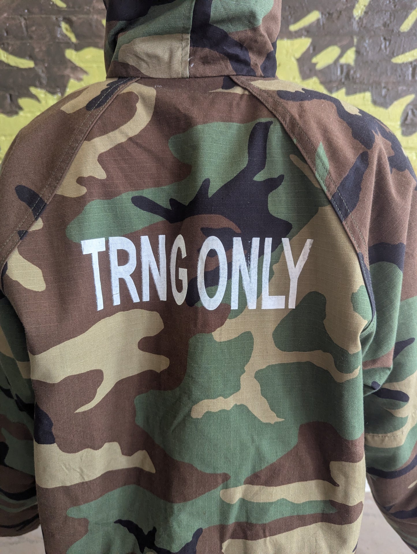Camouflage jacket with 'TRNG ONLY' text on a camouflage-patterned background
