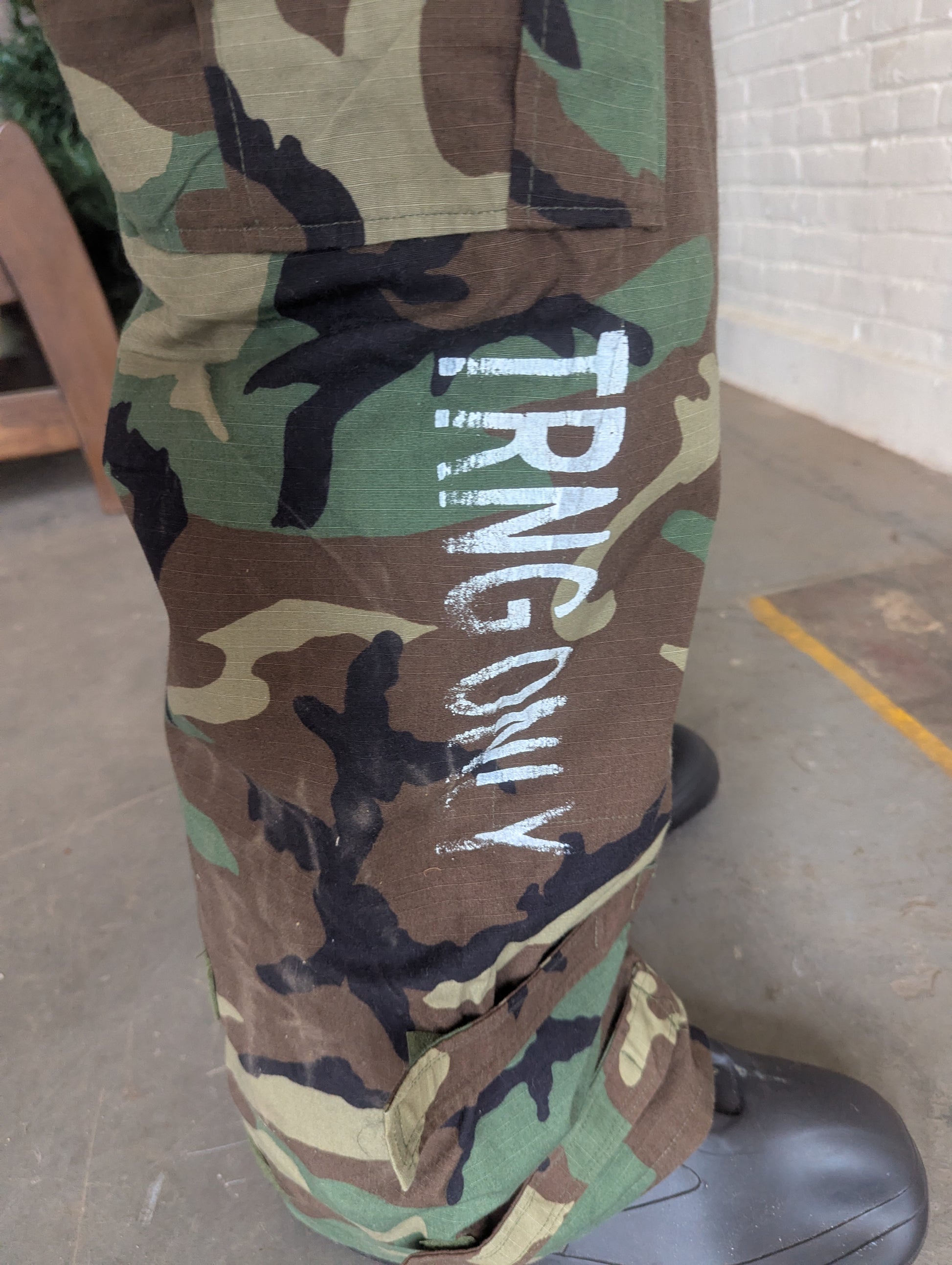 Camouflage pants with 'IRVING' text on a concrete floor.