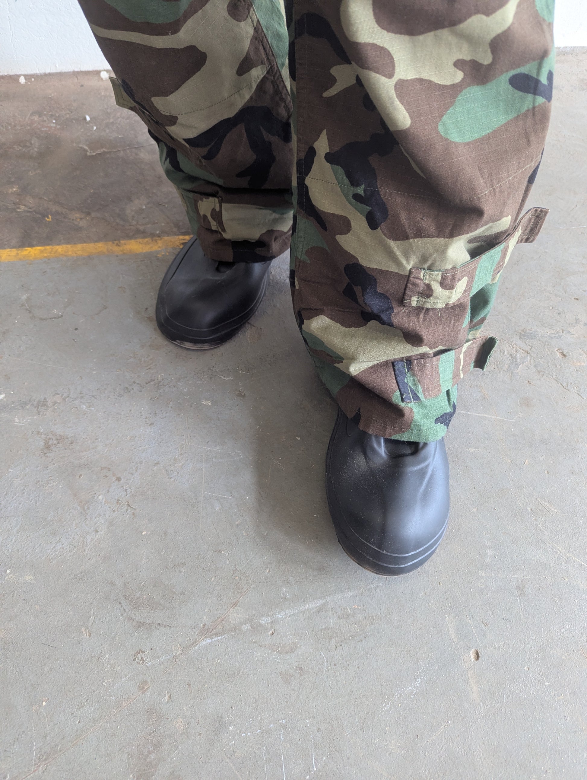 Camouflage pants and black boots on a concrete floor