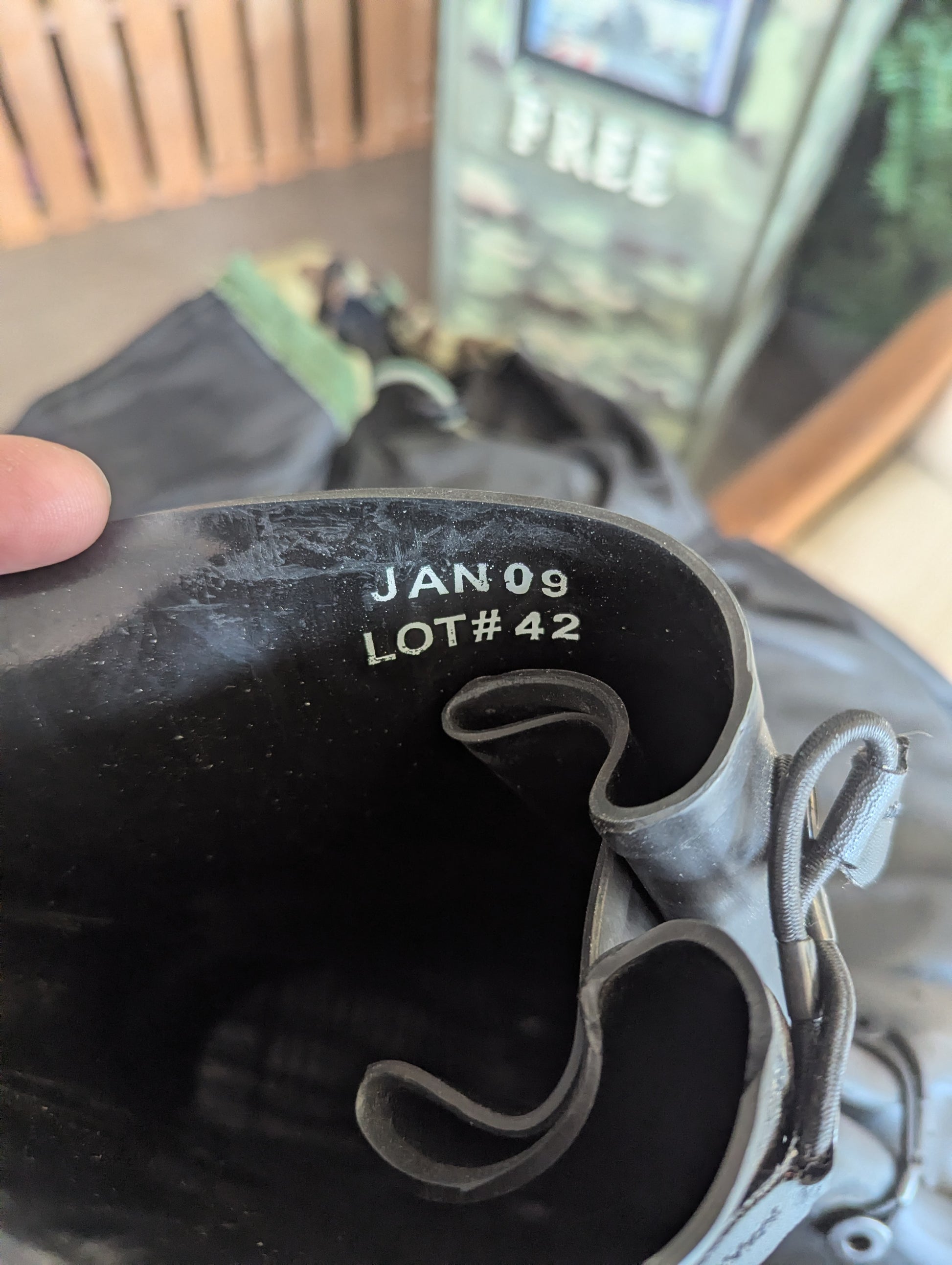 Close-up of a black boot with 'JAN 09 LOT #42' text, held by a hand.