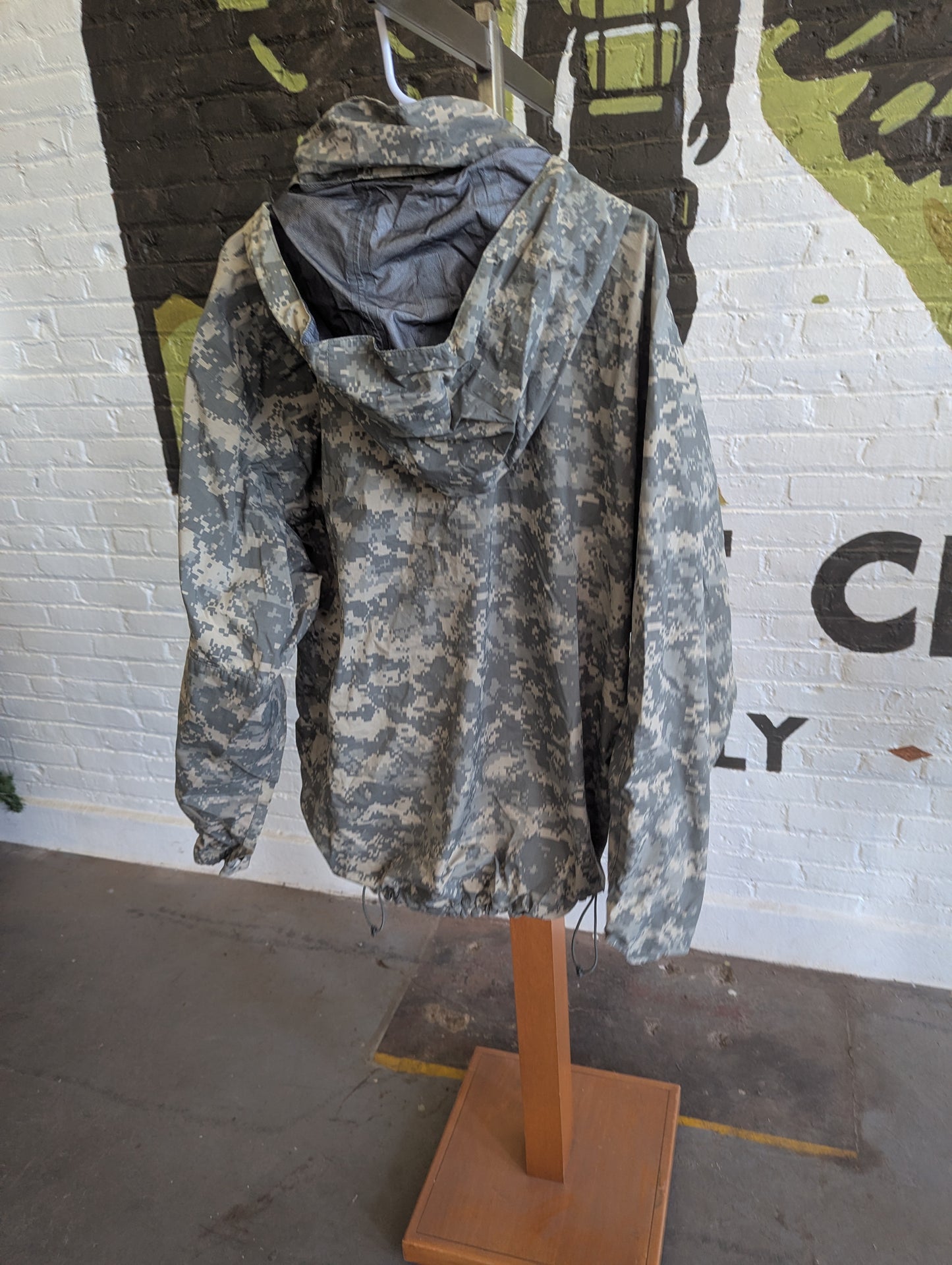Camouflage jacket on a mannequin stand with a graffiti-style wall in the background