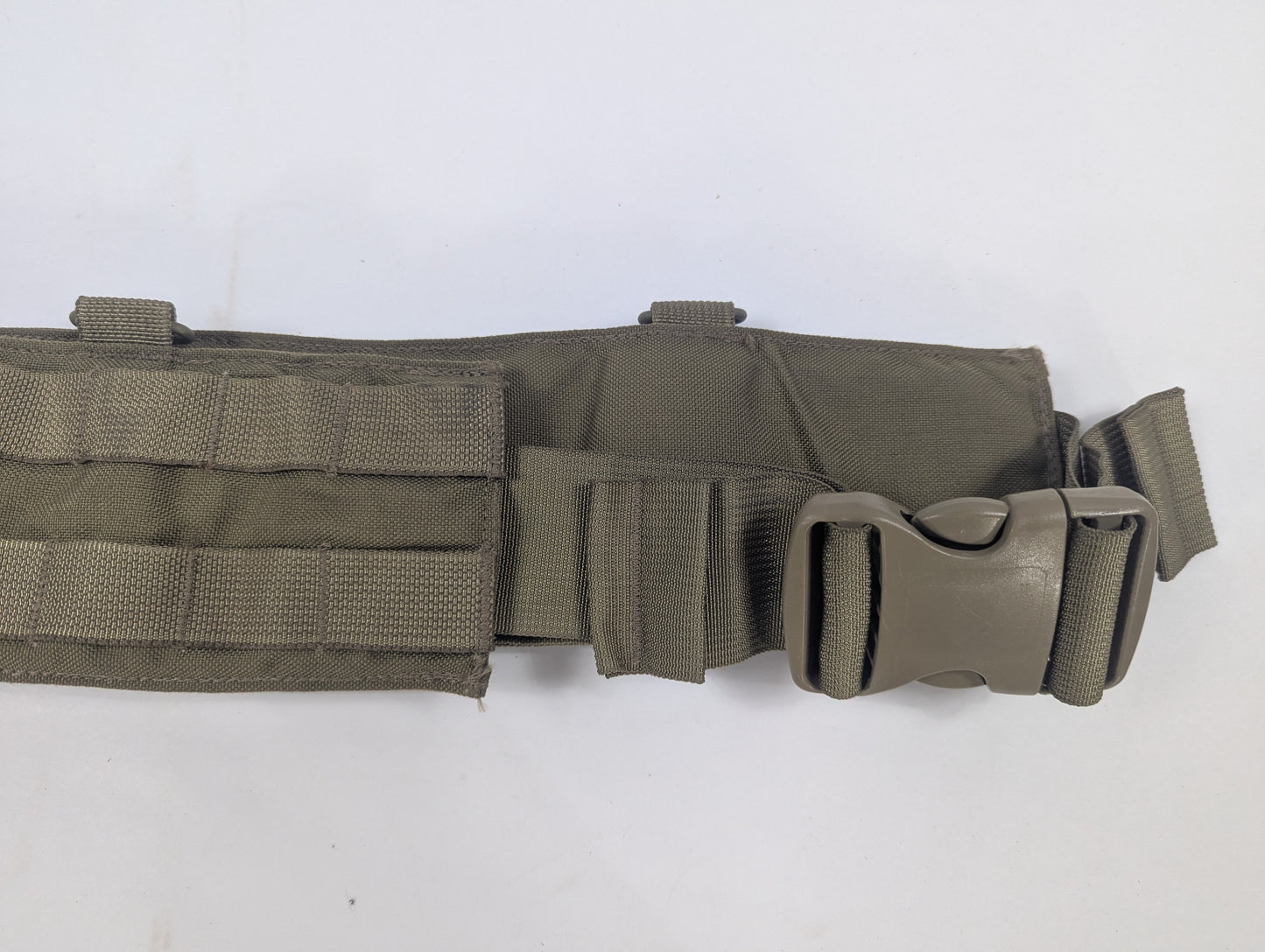 An olive drab tactical belt with a quick-release plastic buckle, displayed on a white circular stand against a white fabric backdrop.