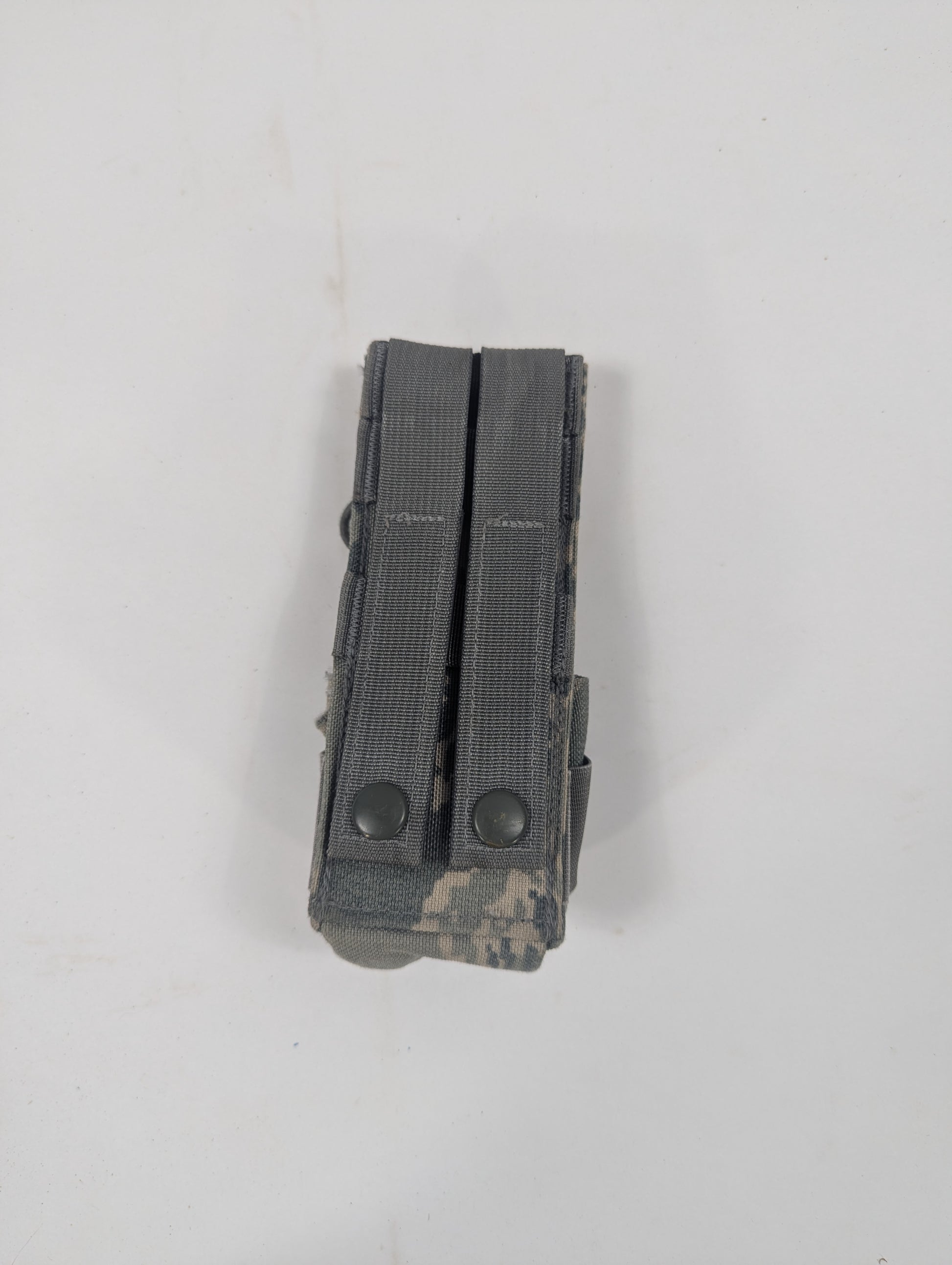 A dark gray tactical dual magazine with a digital camouflage pattern on the base, photographed on a plain off-white background.