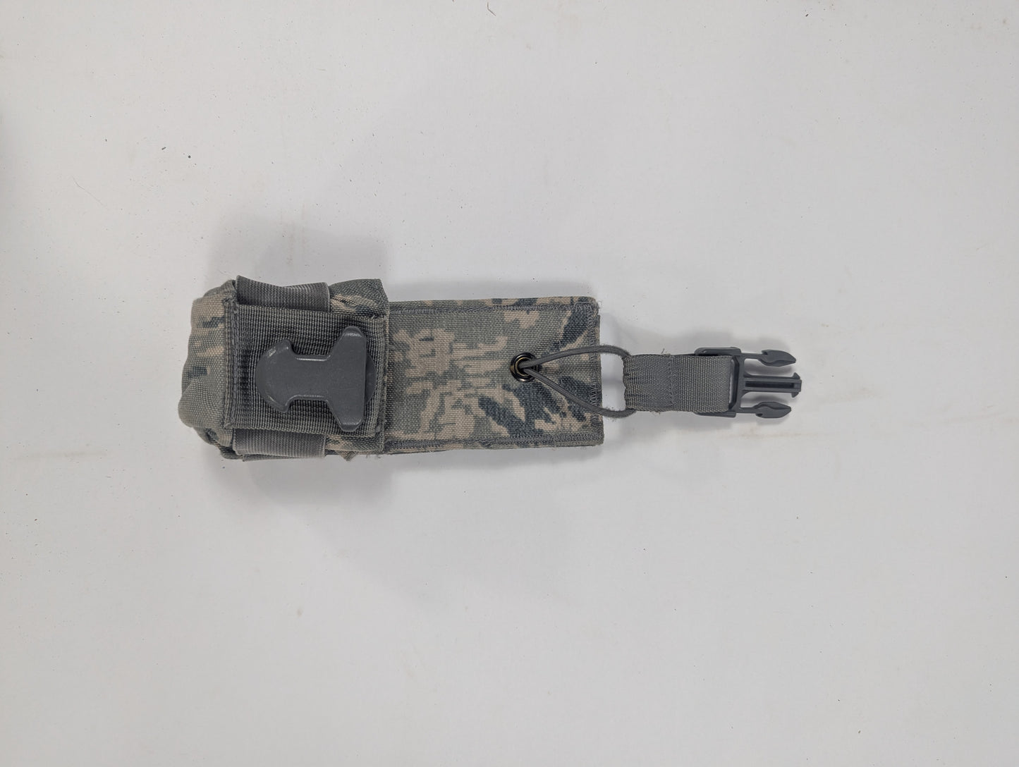 A small tactical pouch in a gray and brown digital camouflage pattern, featuring a black plastic quick-release buckle on the side, shown on a plain light gray background.