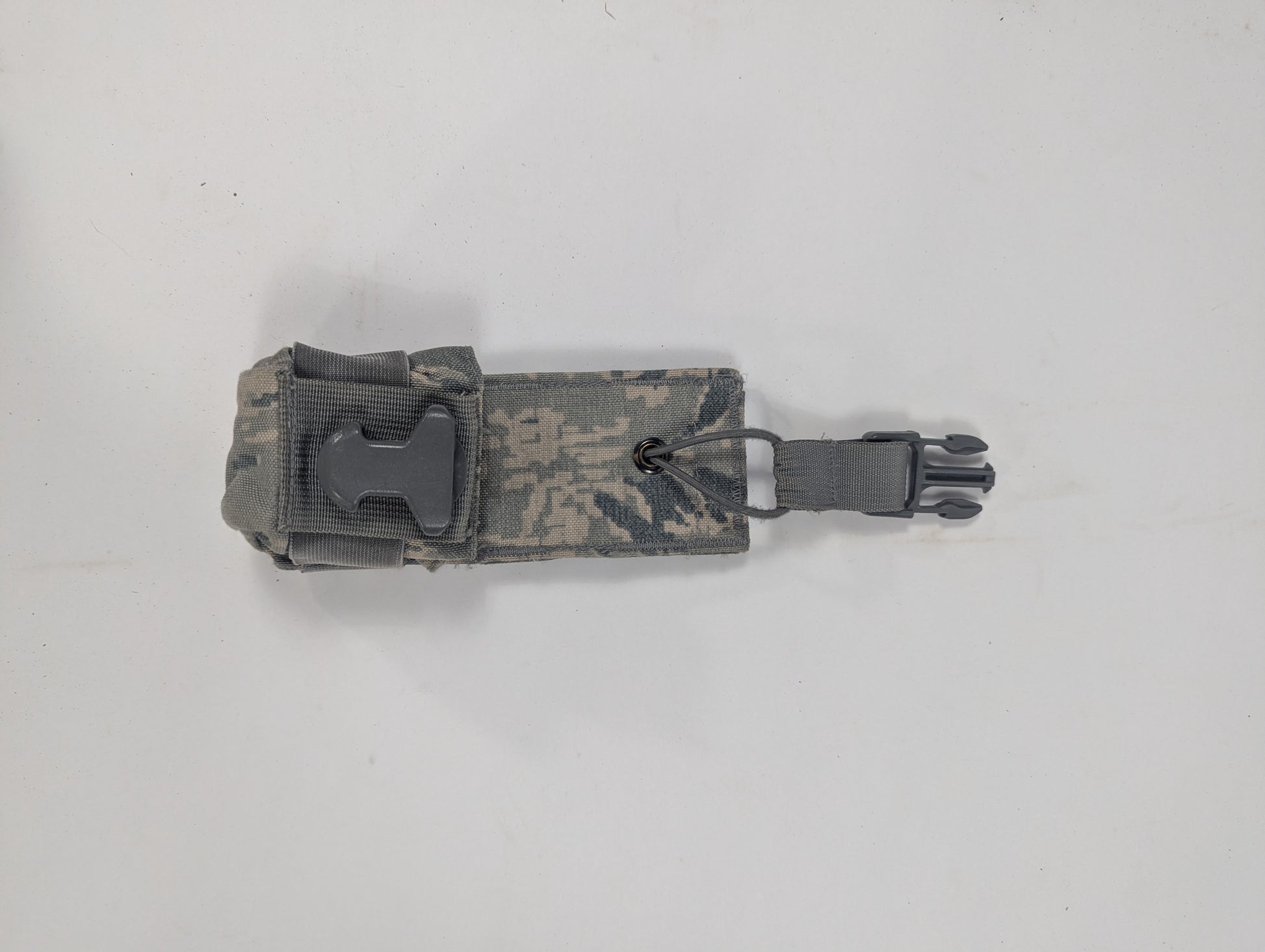 A small tactical pouch in a gray and brown digital camouflage pattern, featuring a black plastic quick-release buckle on the side, shown on a plain light gray background.