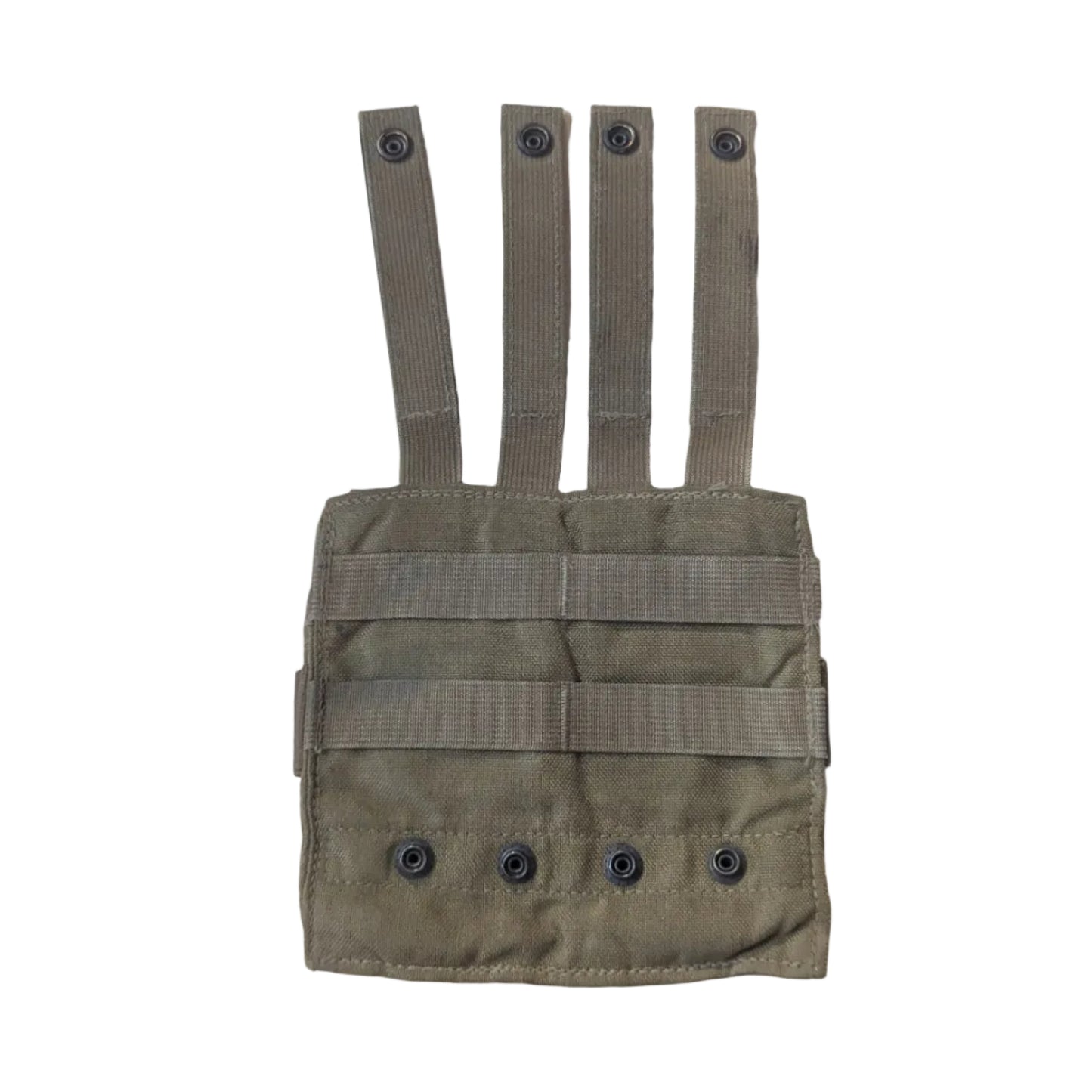 A tan tactical utility pouch with four webbing straps, laid flat on a light-colored wooden table. Parts of a person's legs and feet are visible on the left, and some camouflage fabric and a blue tool are visible on the right.