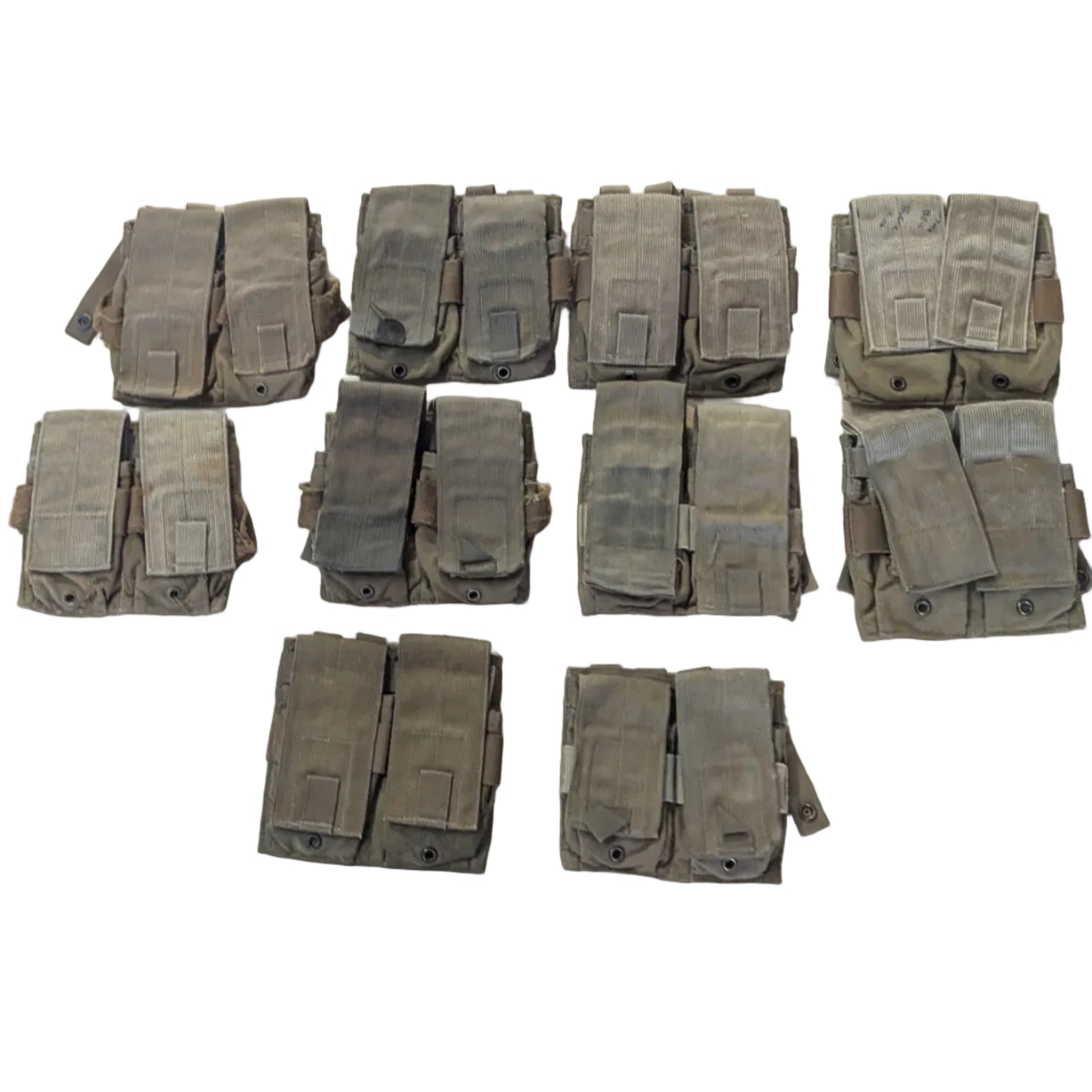 Ten pairs of tactical utility pouches in a coyote brown color arranged on a light-colored workbench, with a workshop floor and stool visible around the table.