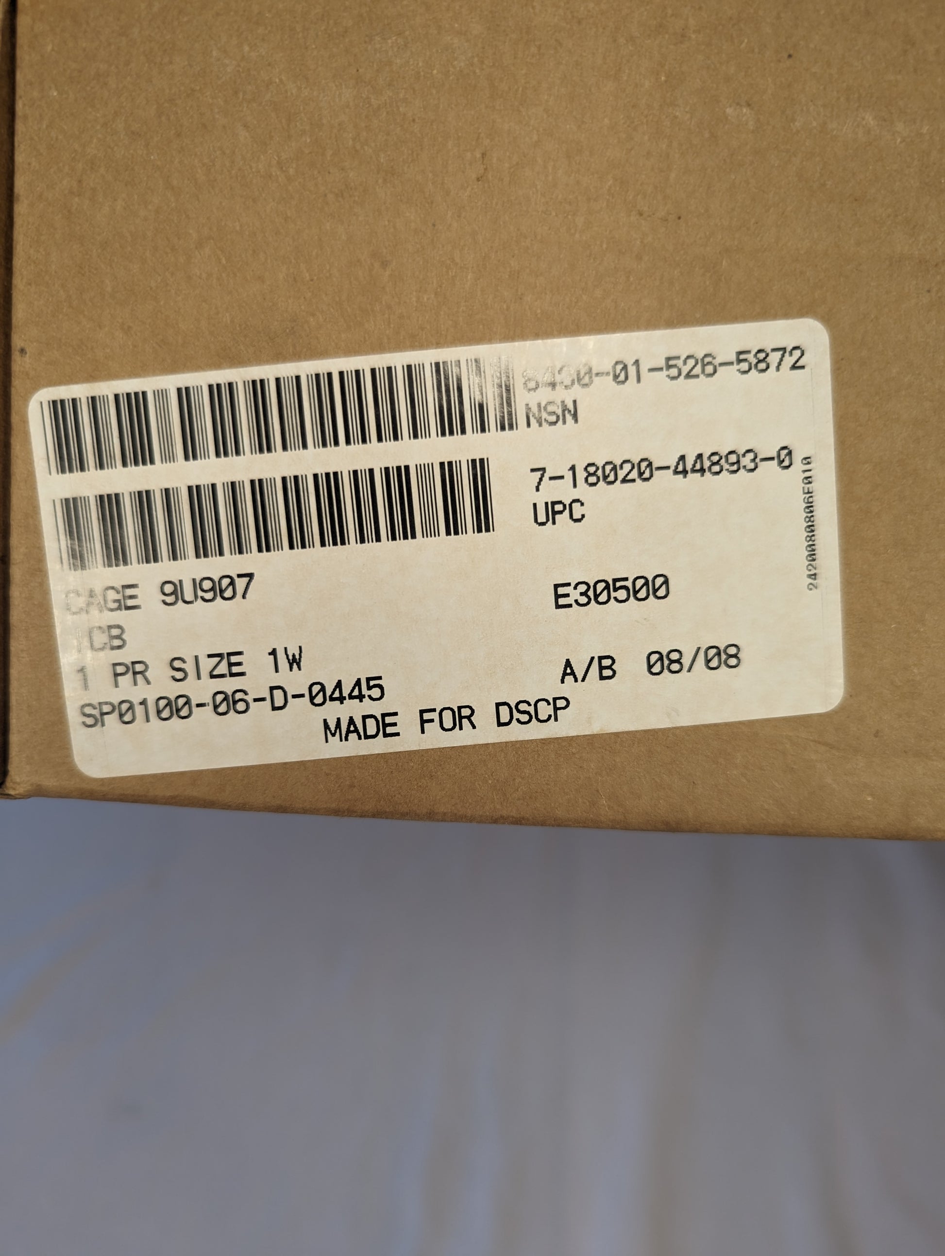 A close-up photograph of the issue label on the Bates Cold Weather Combat Boot box, displaying the size '1W', the National Stock Number 8430-01-526-5632, and 'MADE FOR DSCP' text.