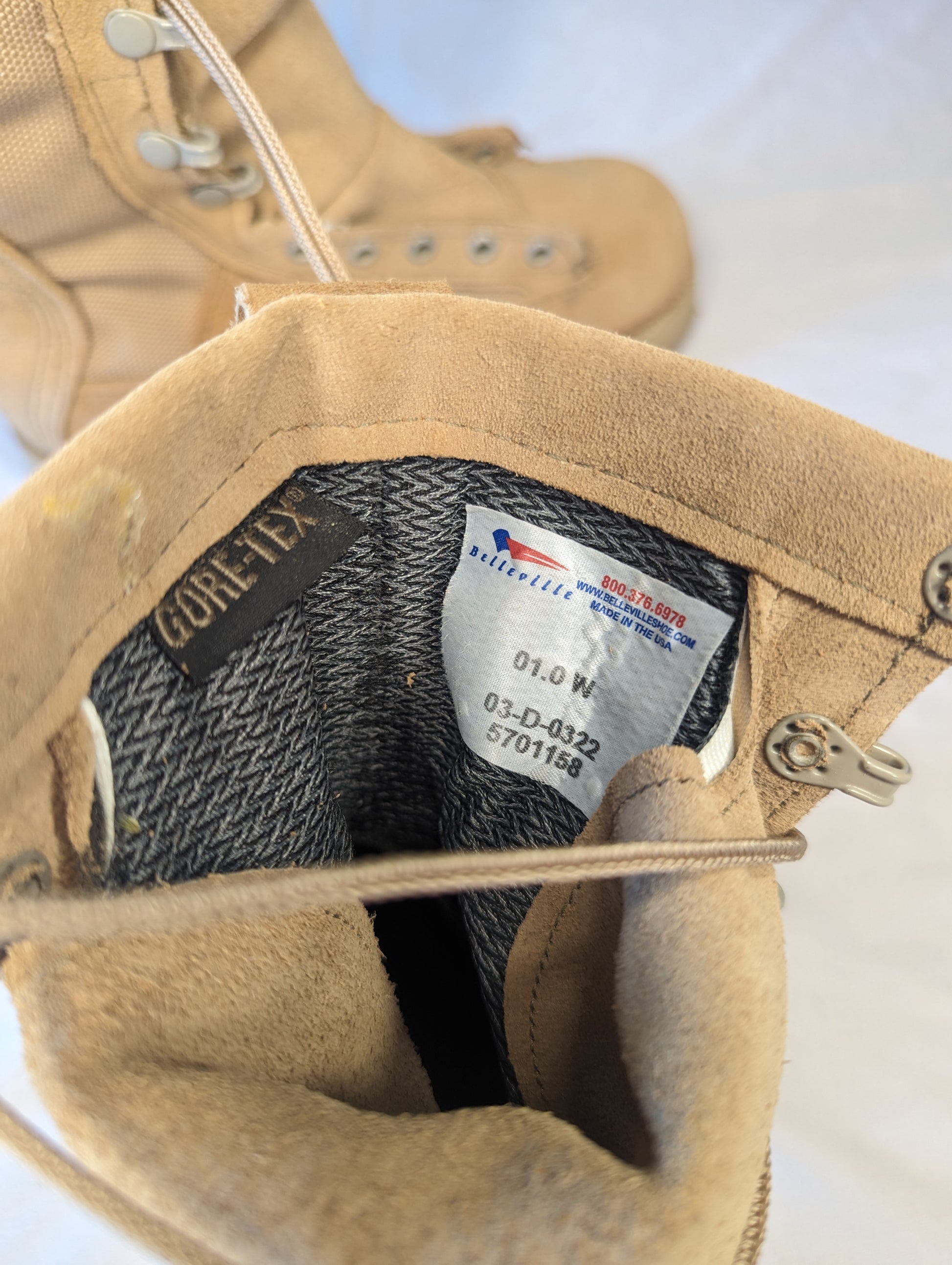 A close-up view of the tan Belleville Cold Weather Combat Boot collar, revealing the Gore-Tex waterproof lining label, the size marking '01.0 W', and the U.S. Military stock numbers.
