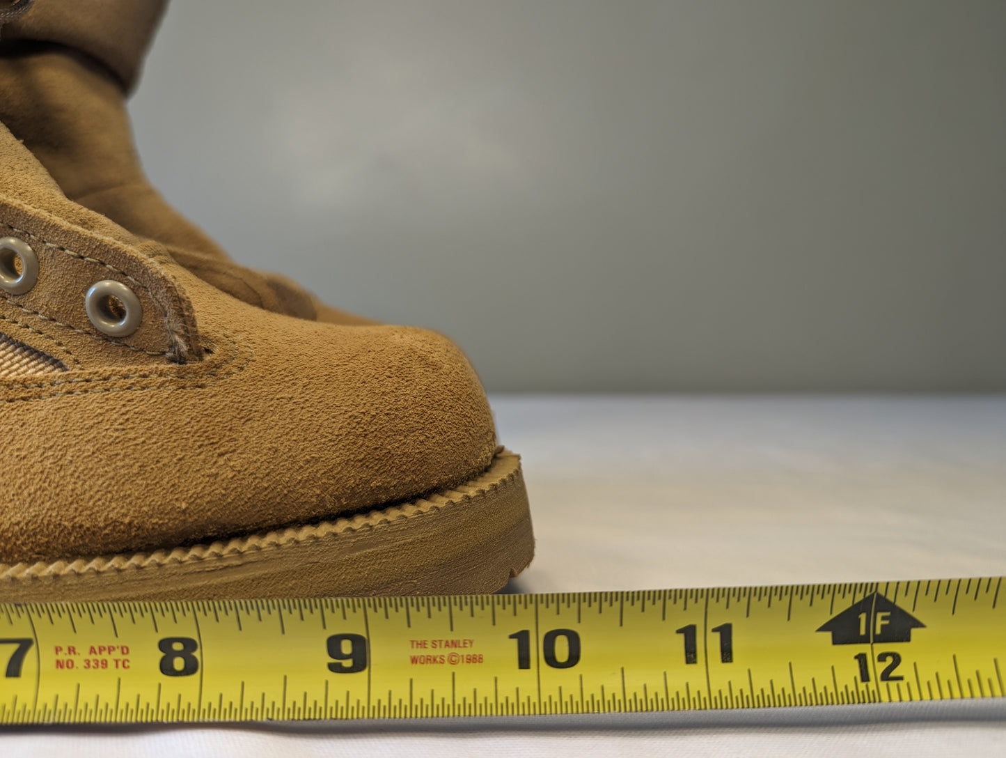 A close-up view of the tan suede Belleville Cold Weather Combat Boot, with a yellow tape measure placed alongside the sole to demonstrate the overall length and size measurement.