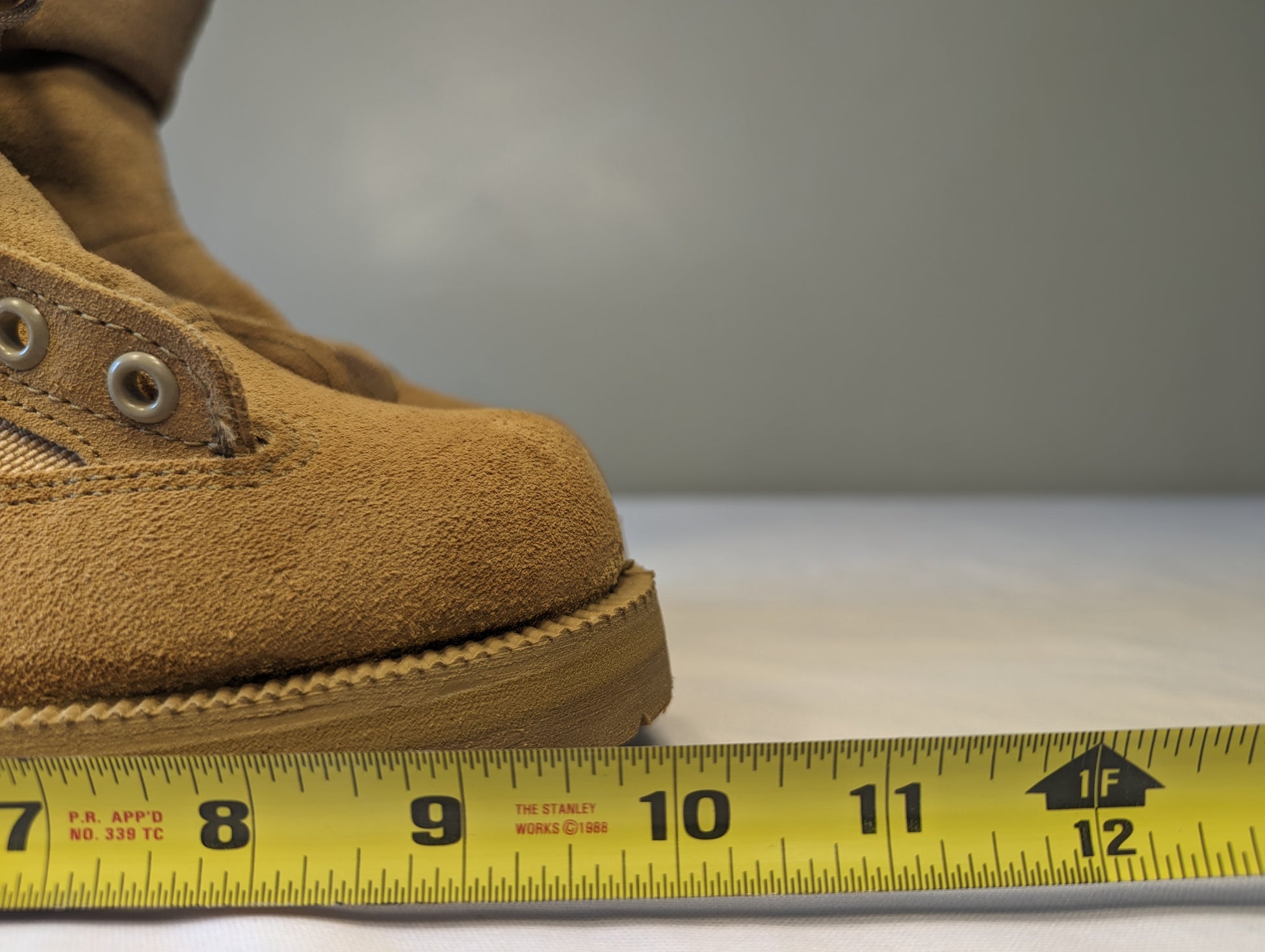 A close-up view of the tan suede Belleville Cold Weather Combat Boot, with a yellow tape measure placed alongside the sole to demonstrate the overall length and size measurement.