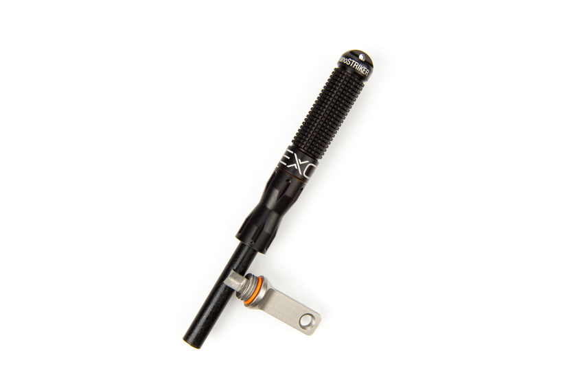 A close-up studio shot of the black nanoSTRIKER XL fire starter, unscrewed and disassembled to show the compact handle, the internal ferrocerium rod, and the striker piece on a white background.