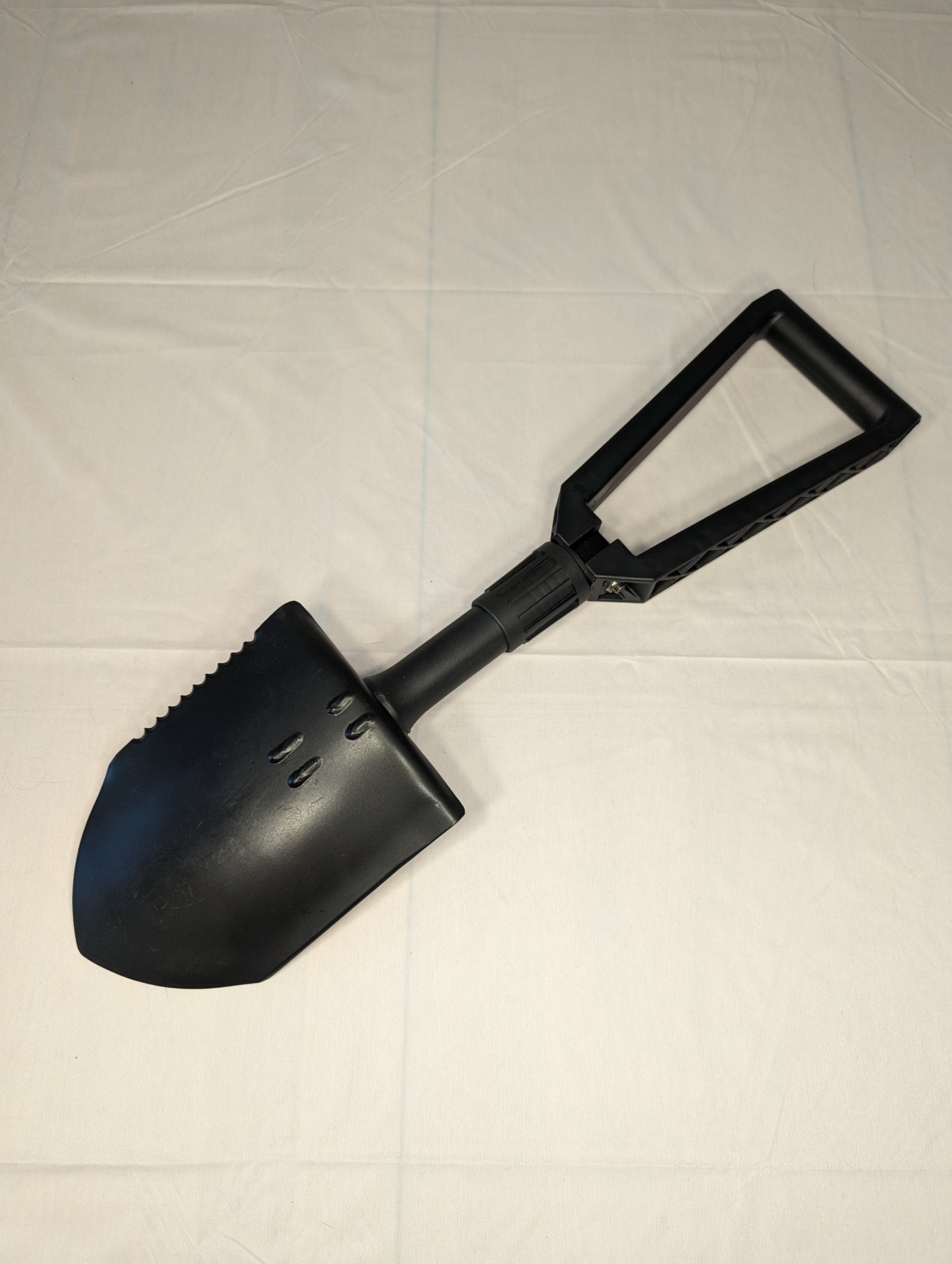 A black Gerber Entrenching Tool (E-Tool) shown fully extended on a white background, featuring a serrated steel shovel blade and a black triangular handle.