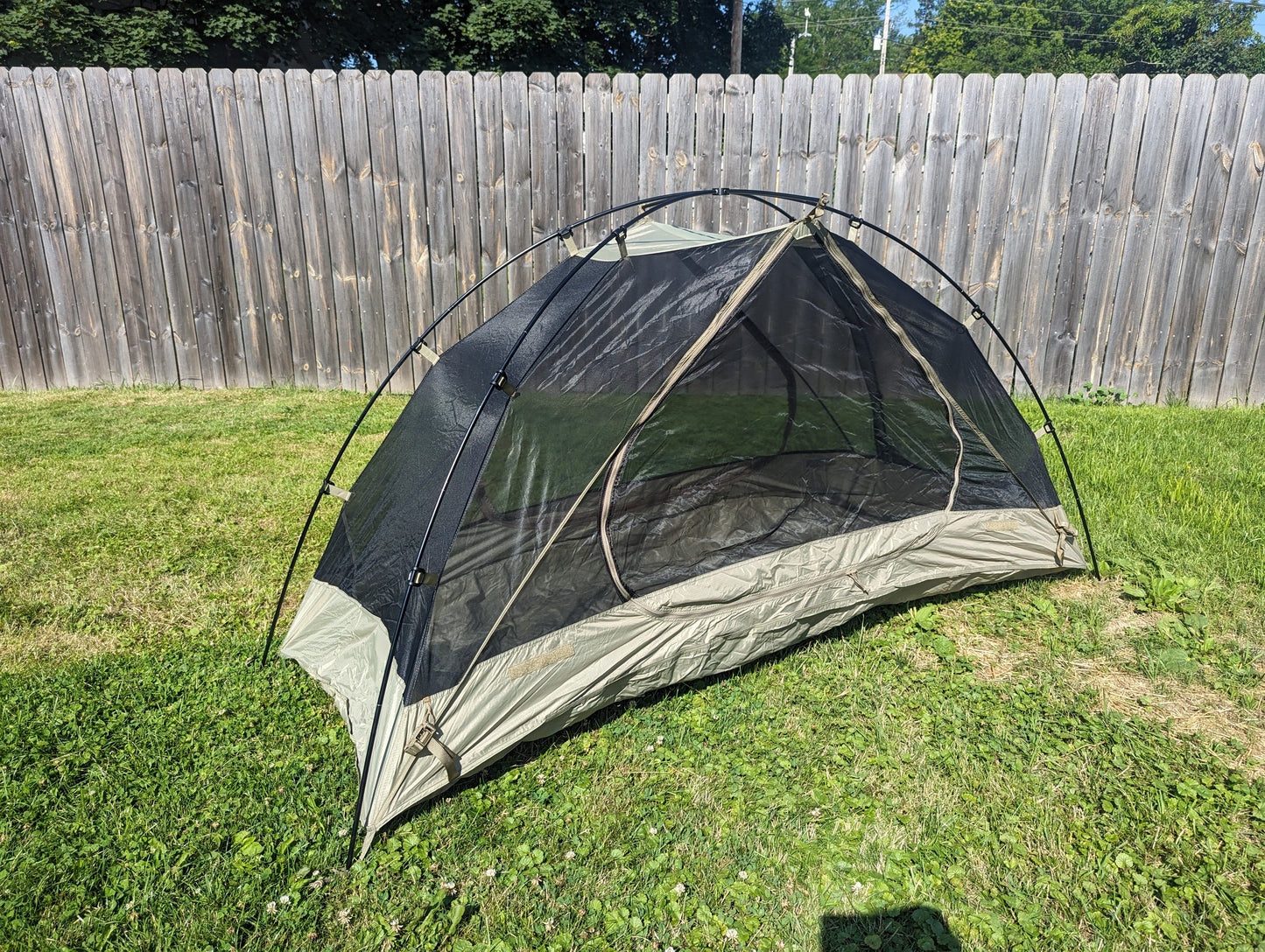 A U.S. Military Litefighter 1-Man Combat Shelter inner tent pitched outdoors on grass, featuring a black mesh canopy and tan nylon floor, highlighting the full structure without the rainfly.