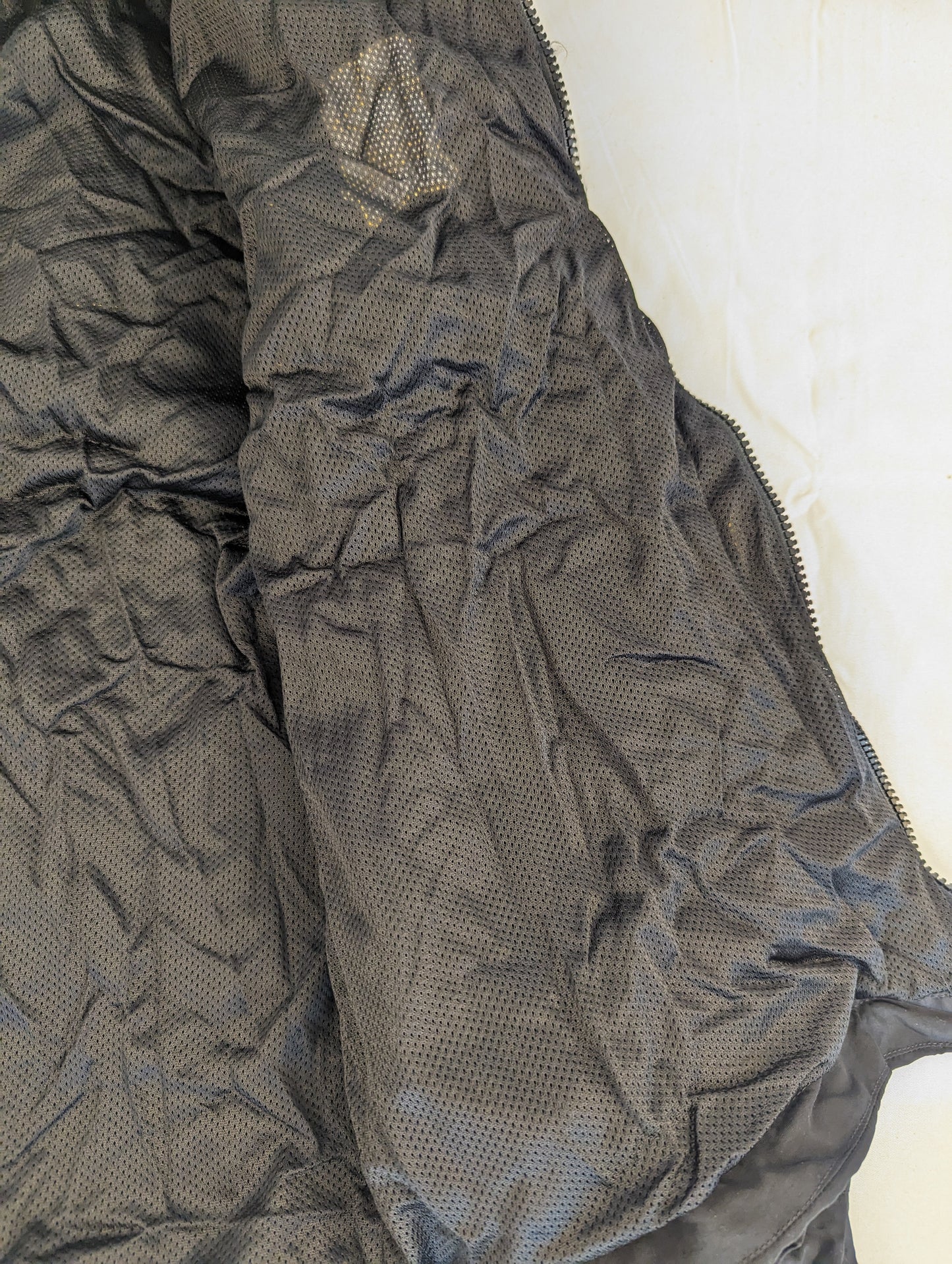A close-up detail view of the black mesh lining inside the U.S. Army Physical Training (PT) jacket, highlighting the breathable fabric texture.