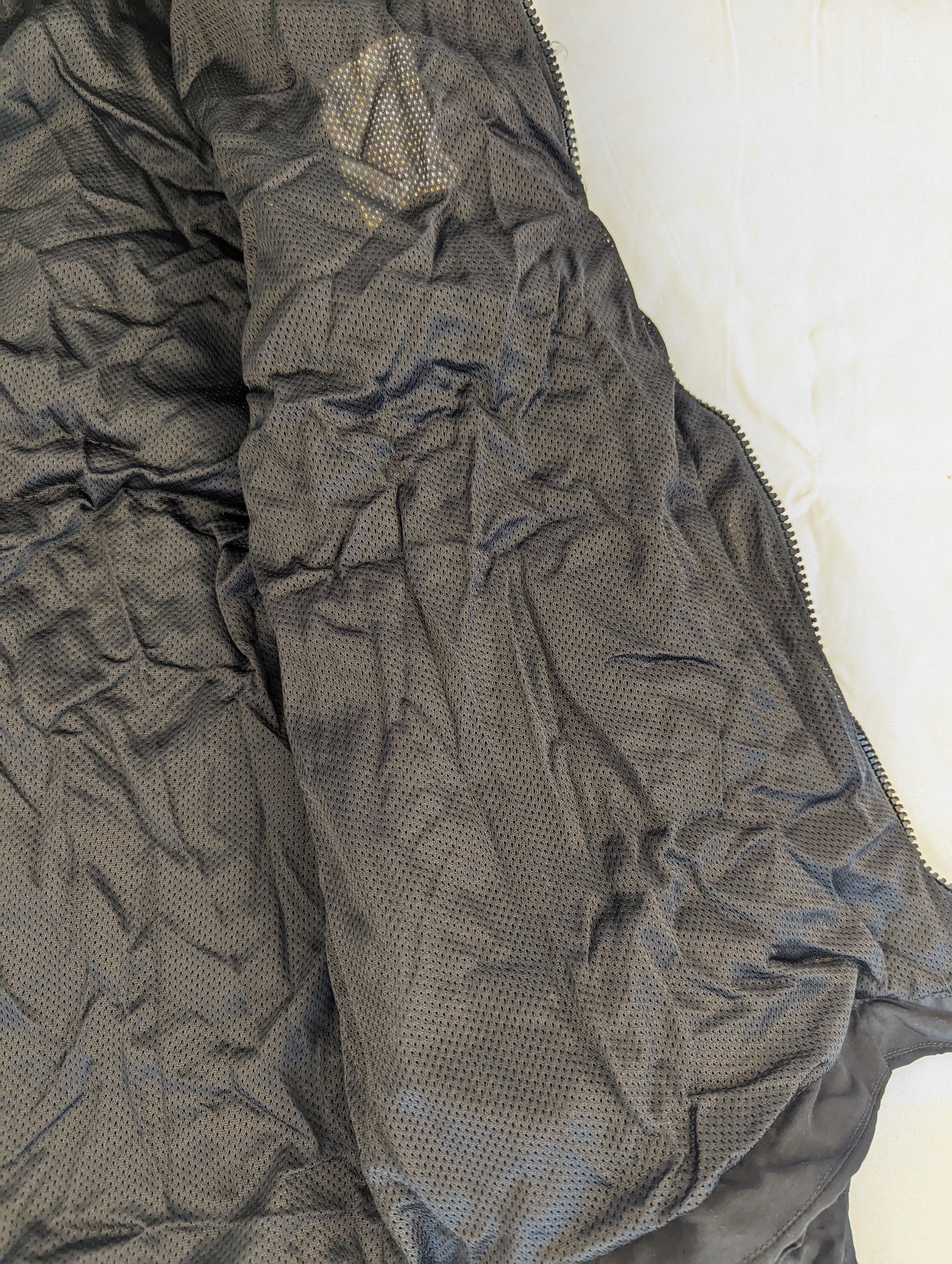 A close-up detail view of the black mesh lining inside the U.S. Army Physical Training (PT) jacket, highlighting the breathable fabric texture.