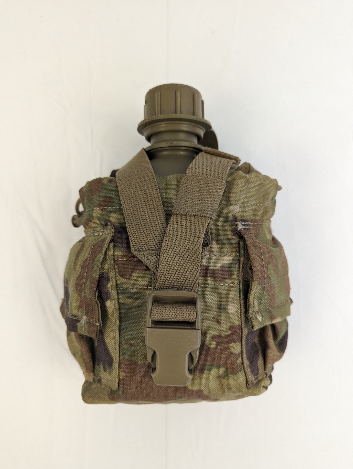 A U.S. Military Surplus 1-quart canteen in olive green, fully contained within a closed OCP/Multicam camouflage pouch, showing the exterior webbing straps and standing upright on a white background.