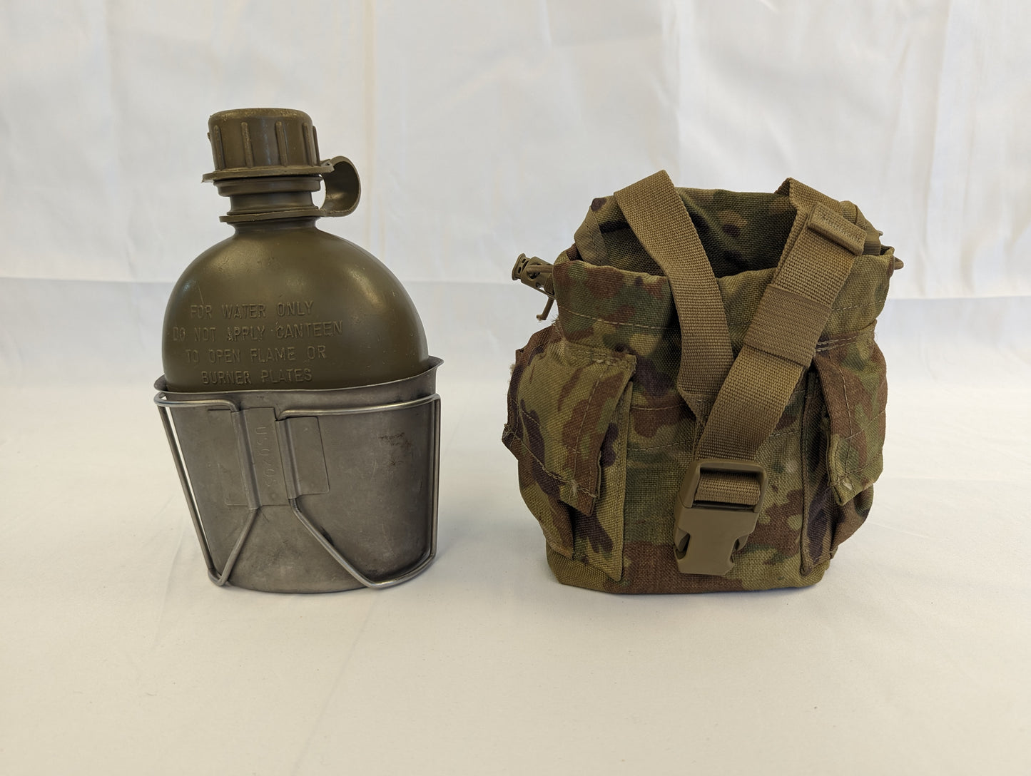 A U.S. Military 1-quart canteen set featuring an olive green plastic canteen nested in a metal cup, displayed next to a closed OCP/Multicam camouflage fabric pouch.