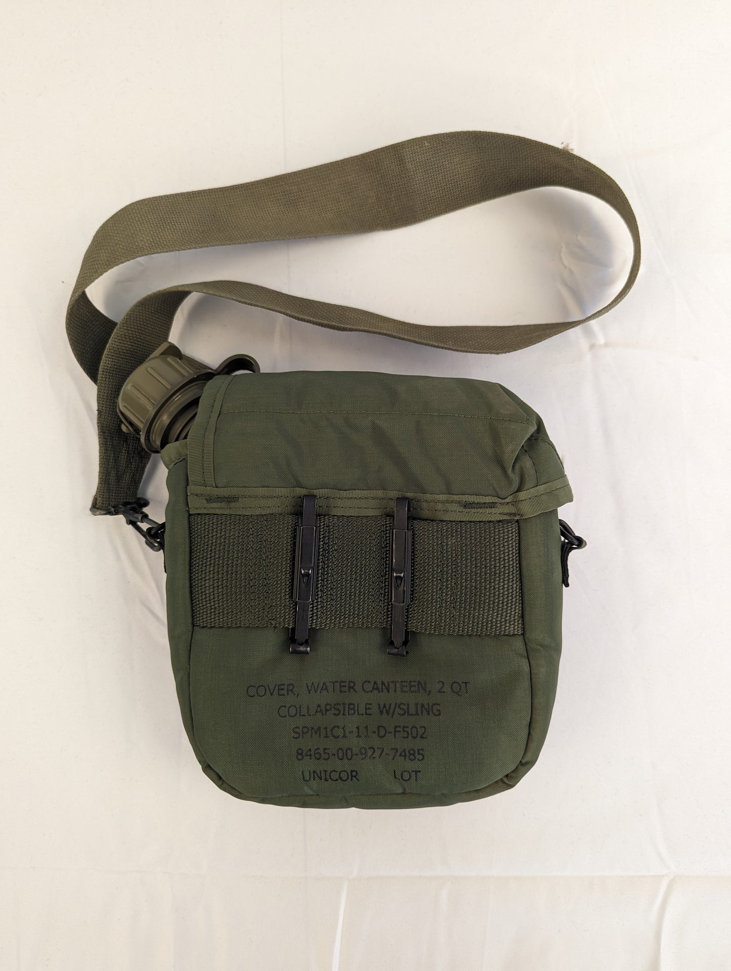A back view of a U.S. Military Surplus 2-quart water canteen cover in olive green, displaying the two black metal ALICE attachment clips, the shoulder sling, and stamped military markings.