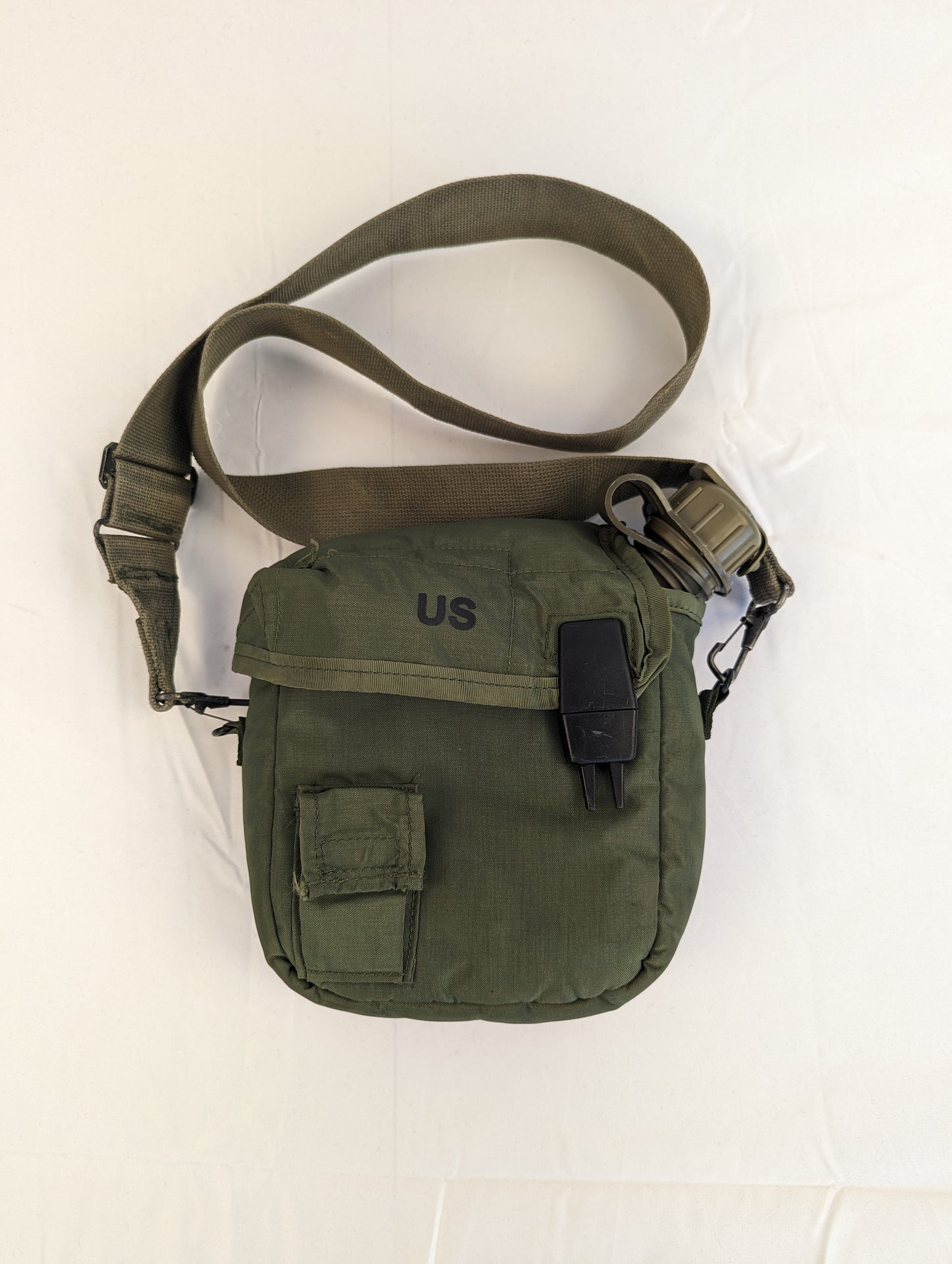 A U.S. Military Surplus 2-quart collapsible water canteen in an olive green cover with a shoulder sling strap, featuring a small utility pocket and stenciled 'US' marking on the front.