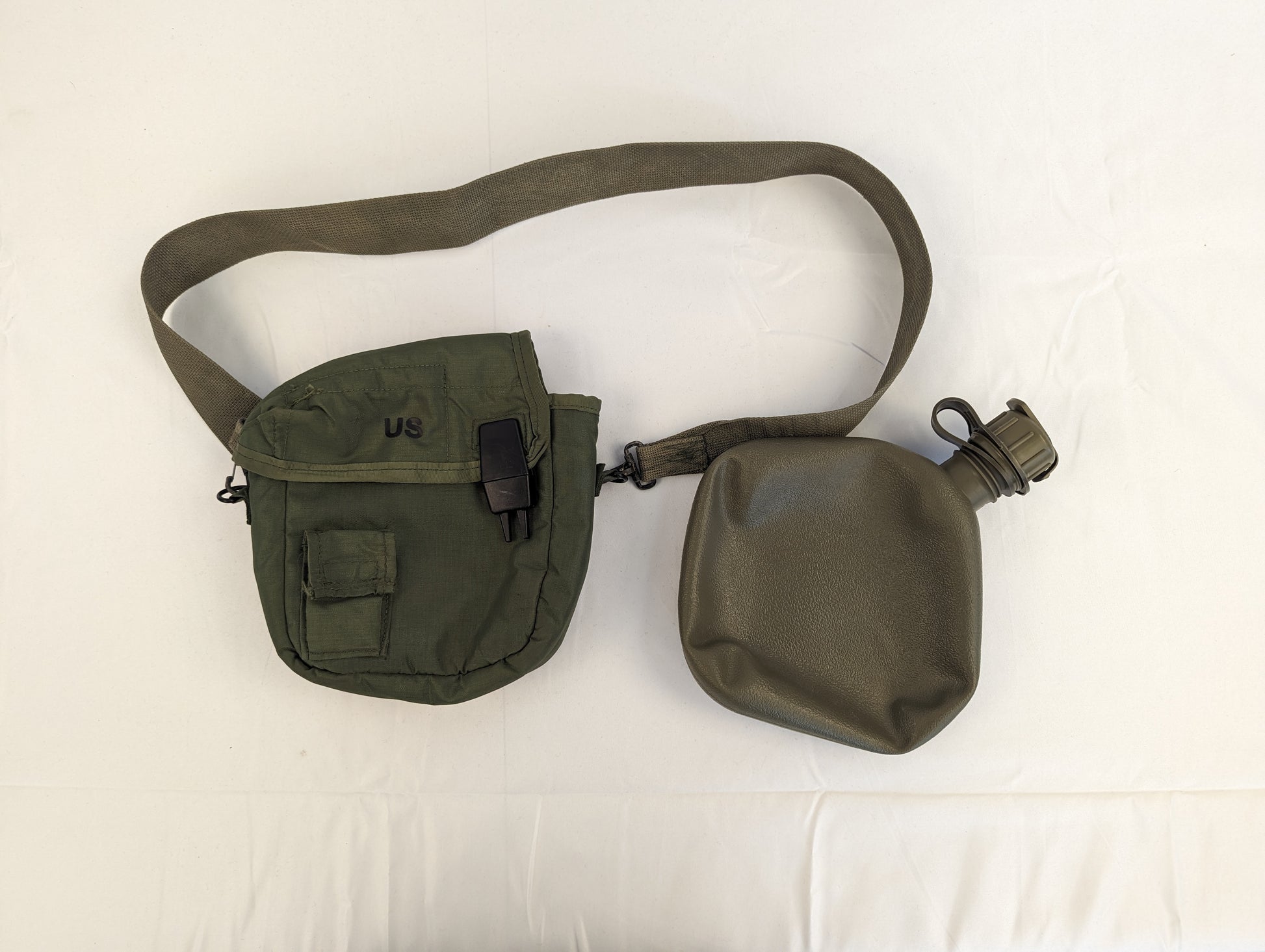 A U.S. Military Surplus 2-quart collapsible water canteen set, displaying the olive green nylon cover with 'US' marking and shoulder sling next to the collapsible bladder and cap on a white background.