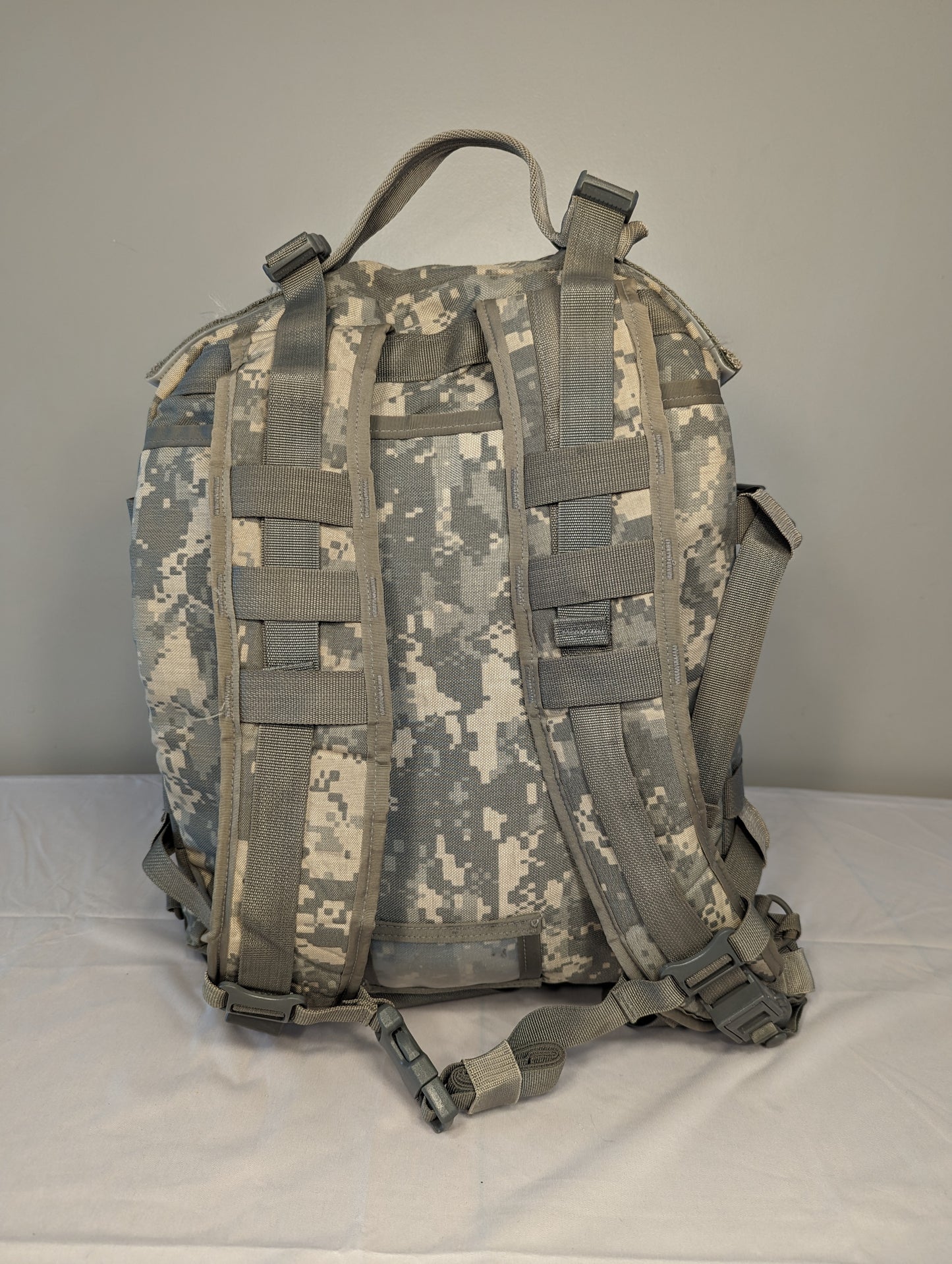 A rear view of a U.S. Military Surplus MOLLE II 3-Day Assault Pack in ACU digital camouflage, highlighting the complete padded shoulder harness, waist belt, and suspension system webbing.