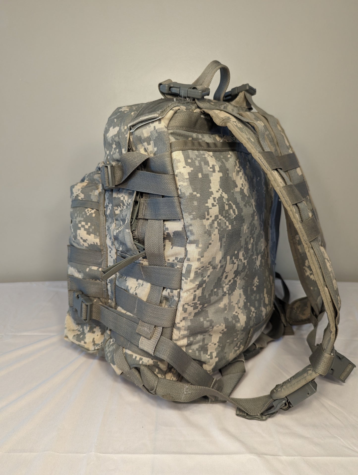 A rear view of a U.S. Military Surplus MOLLE II 3-Day Assault Pack in ACU digital camouflage, highlighting the padded shoulder straps, sternum strap, and entire suspension harness.