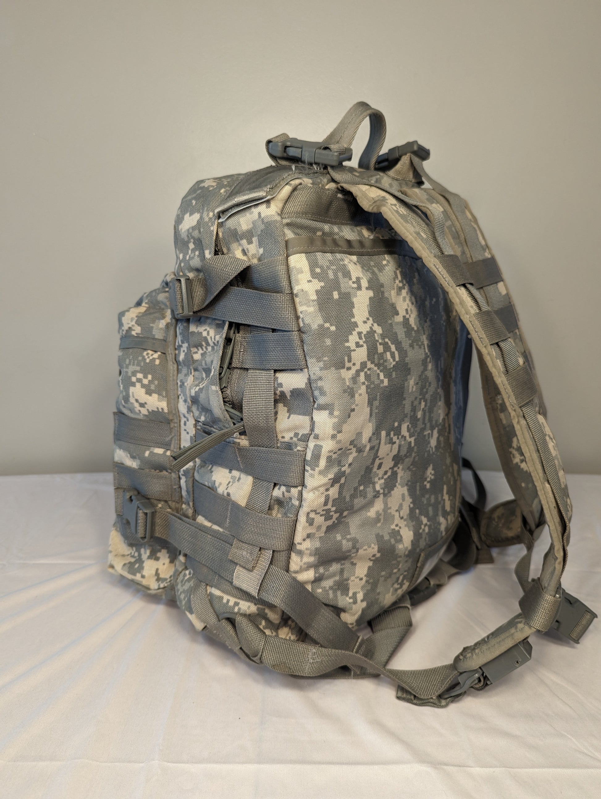 A rear view of a U.S. Military Surplus MOLLE II 3-Day Assault Pack in ACU digital camouflage, highlighting the padded shoulder straps, sternum strap, and entire suspension harness.