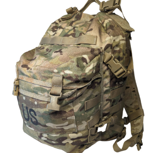 A U.S. Military Surplus 3-Day Assault Pack in OCP/Multicam camouflage, featuring extensive MOLLE webbing, compression straps, and a large stenciled 'US' mark on the front pocket.