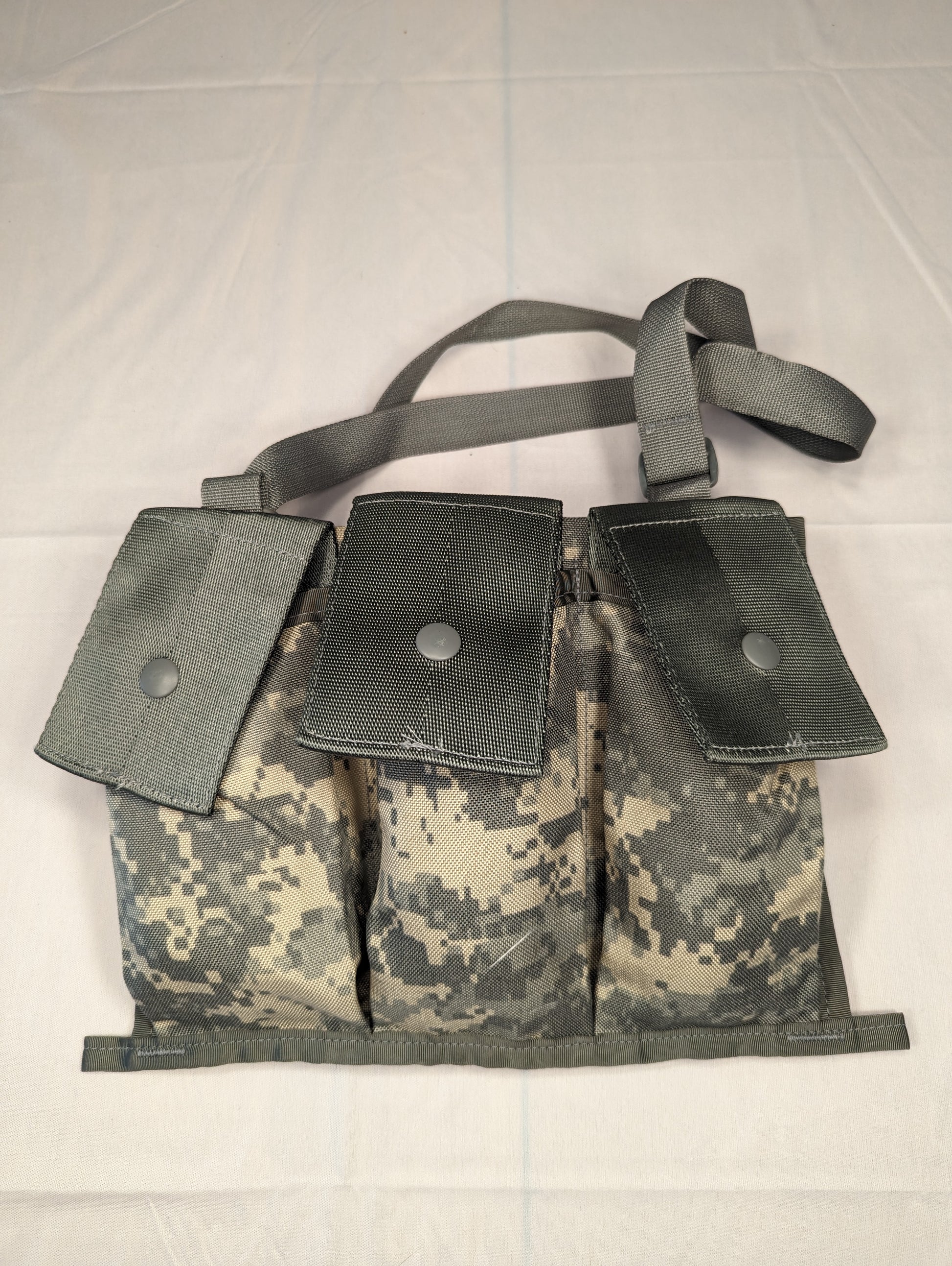 A U.S. Military Surplus MOLLE II Bandoleer in ACU digital camouflage, laid flat, featuring three large magazine pockets with snap-button flaps and an adjustable shoulder strap.