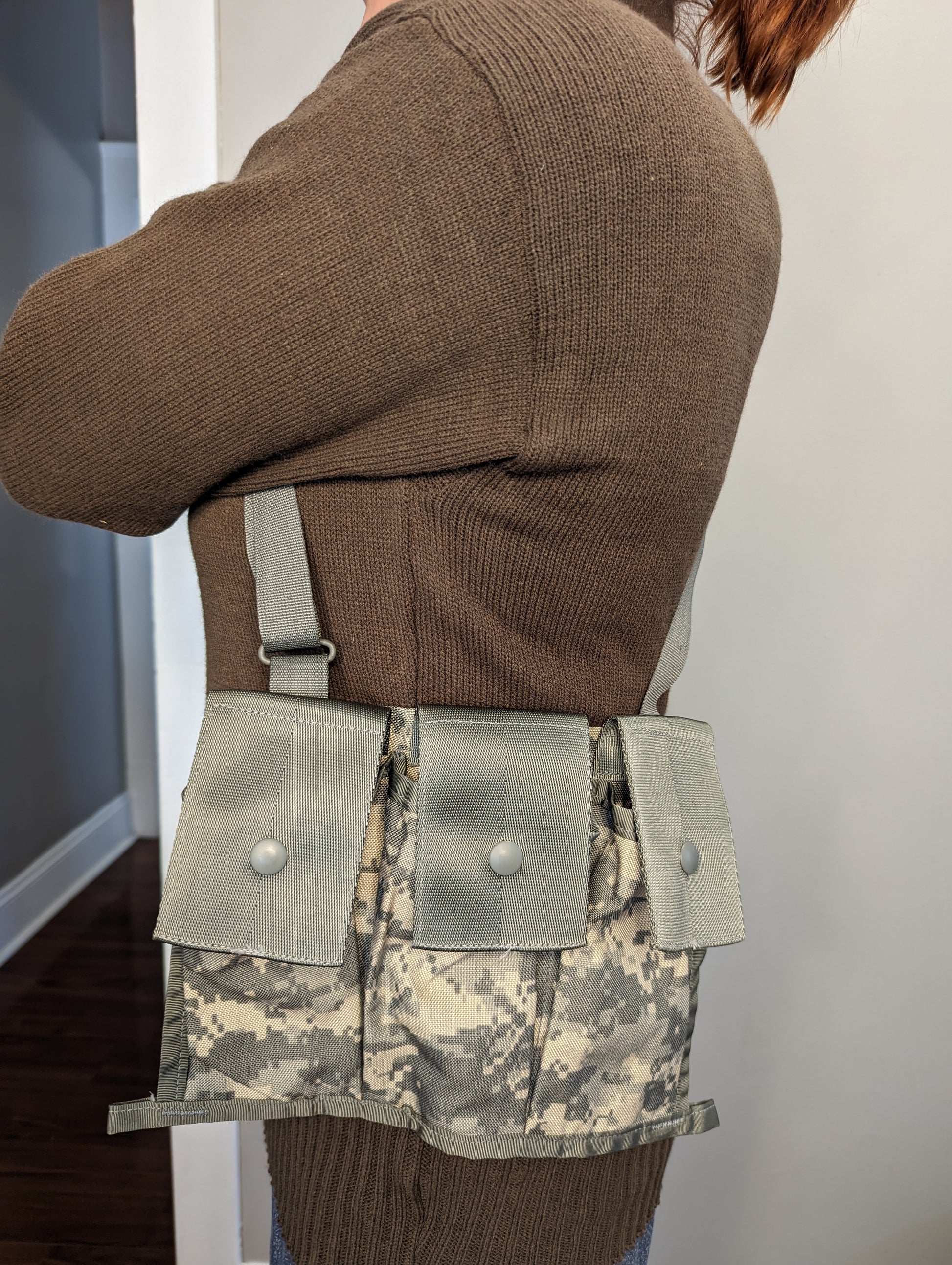 A person wearing a U.S. Military Surplus Bandoleer in ACU digital camouflage slung over their shoulder, showing the three snap-closure pouches and the fit across the chest and torso.