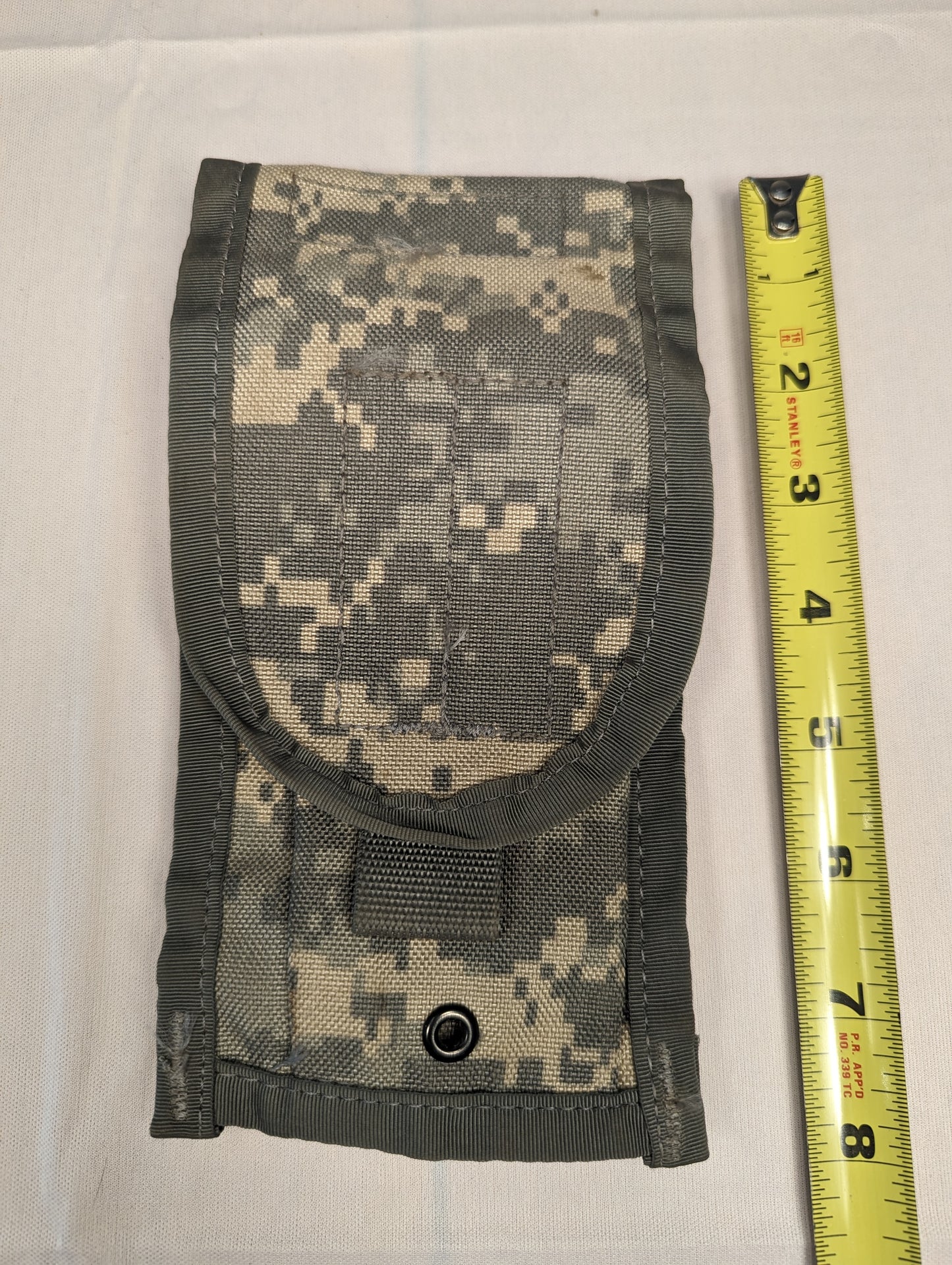 A single U.S. Military Surplus 2-Mag Pouch in ACU digital camouflage, laid flat, with a metal snap closure and a yellow tape measure placed on the side to demonstrate its height of approximately 8 inches.